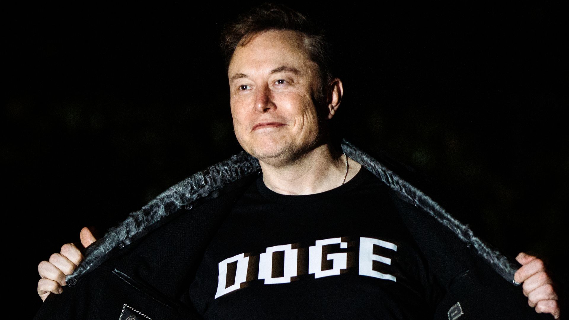 Elon Musk photographed wearing a black shirt that reads "DOGE" in white letters. 
