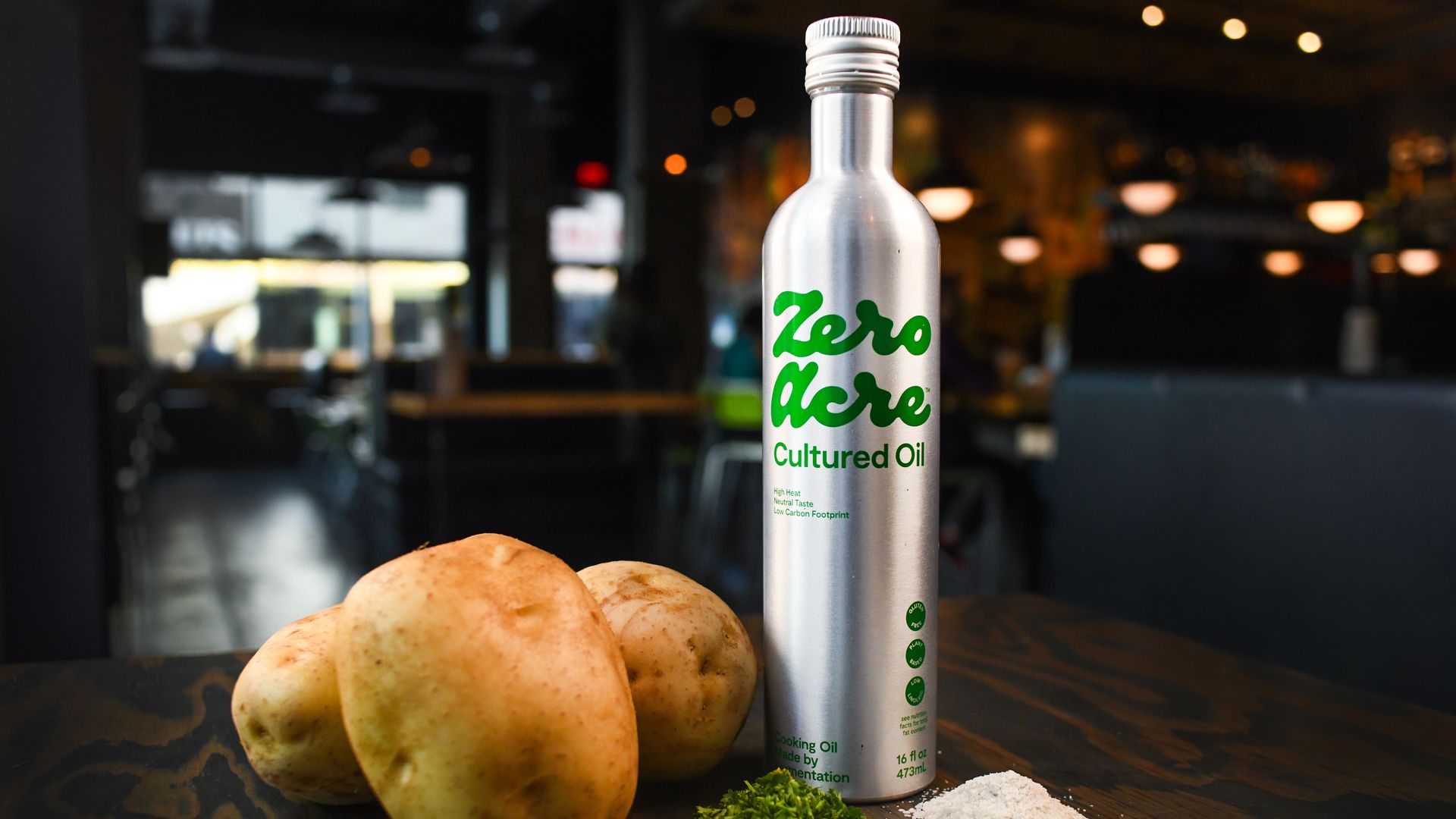 Raw potatoes and an aluminum bottle of Zero Acre Farms cooking oil are displayed on a table.