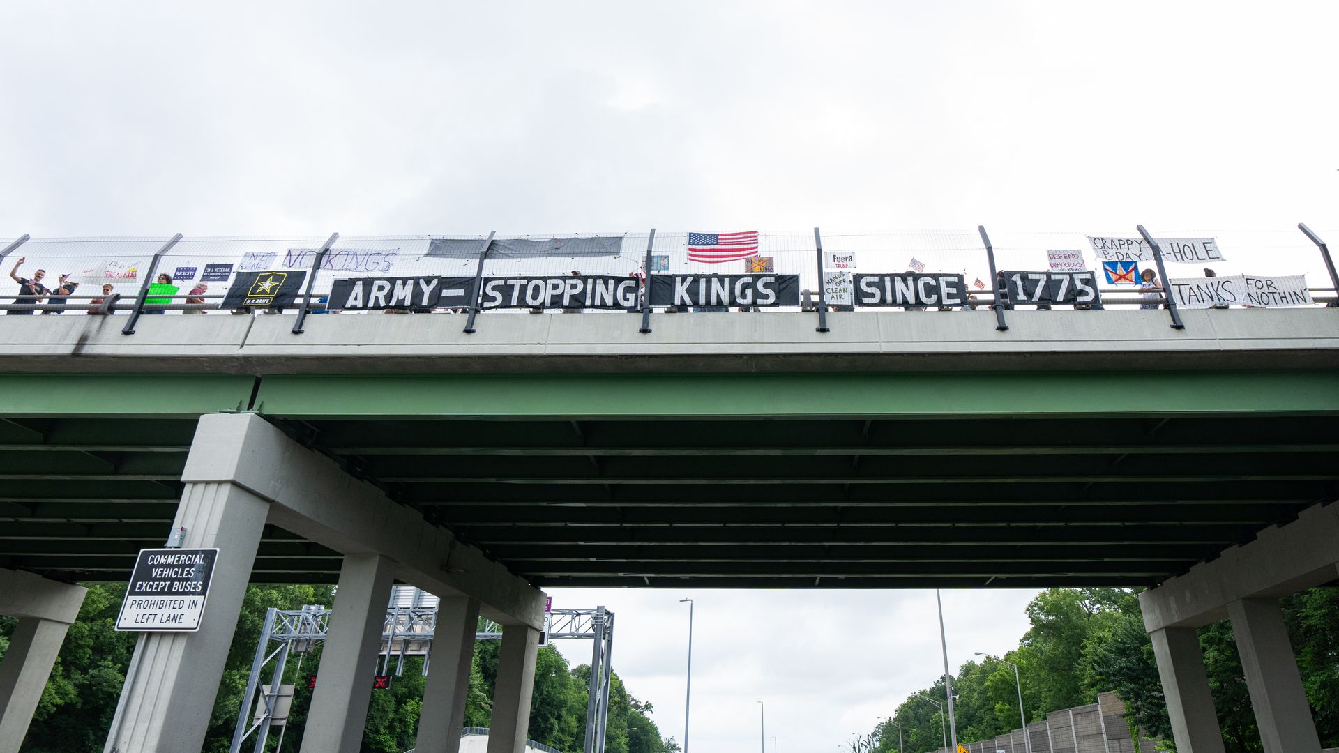  No Kings' activists hang banners and signs on an I-395 highway overpass in Arlington, Va., on Saturday, June 14 before the start of President Donald Trump's military parade in Washington a few miles away. One banner reads "Army-Stopping Kings Since 1775." 