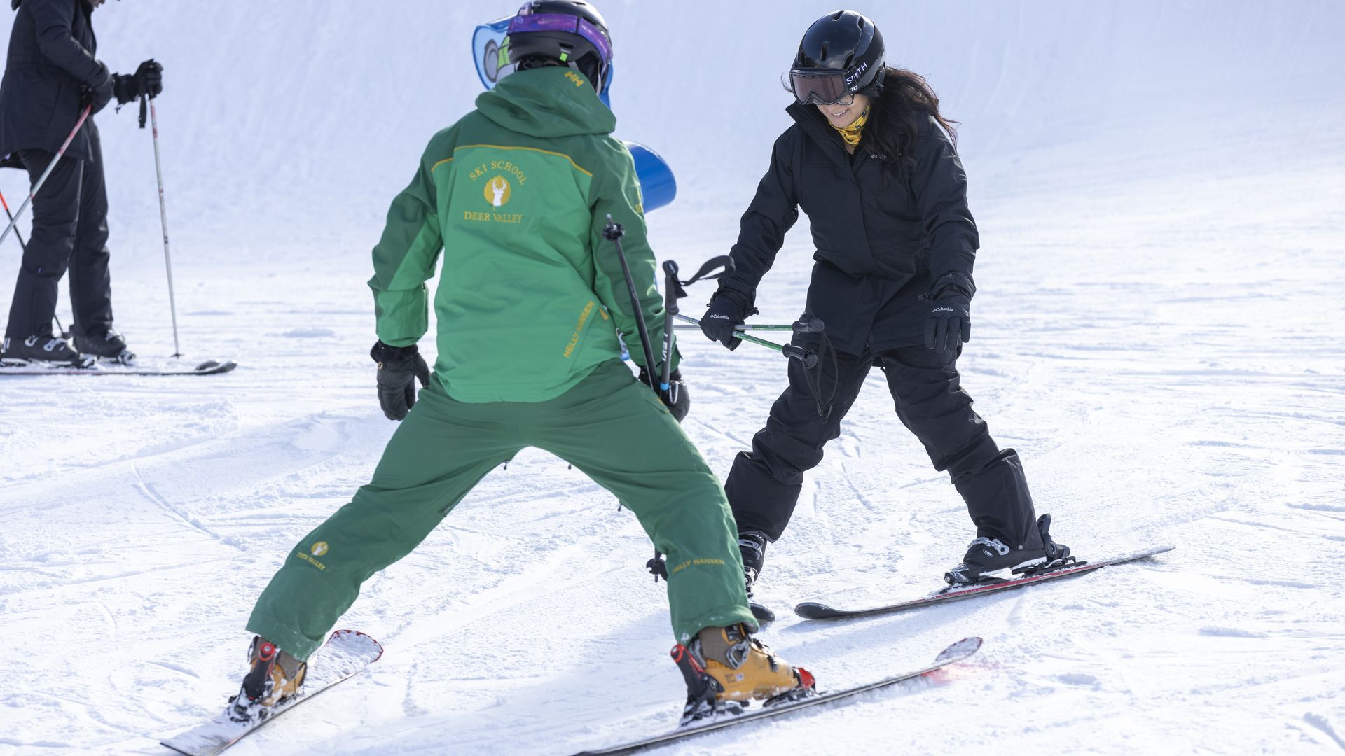 A woman learning to ski with her instructor.