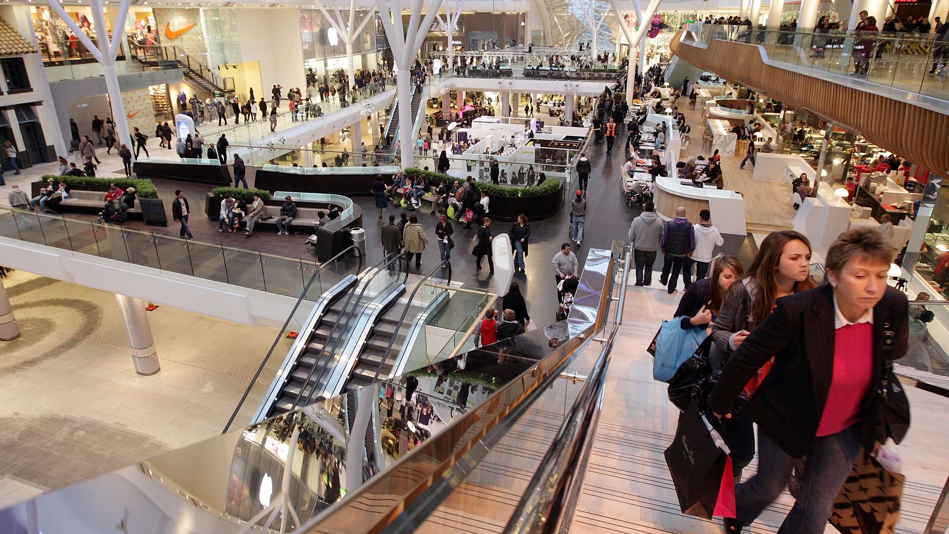 People on an escalator holding shopping bags.