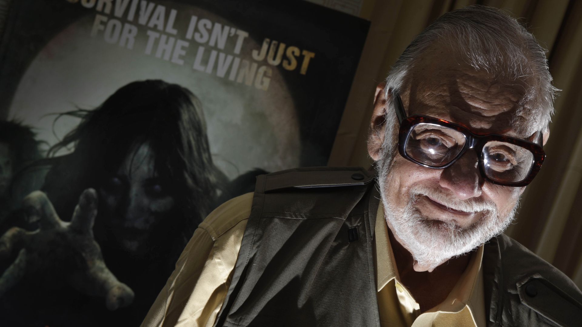 Director George Romero stands next to a poster.
