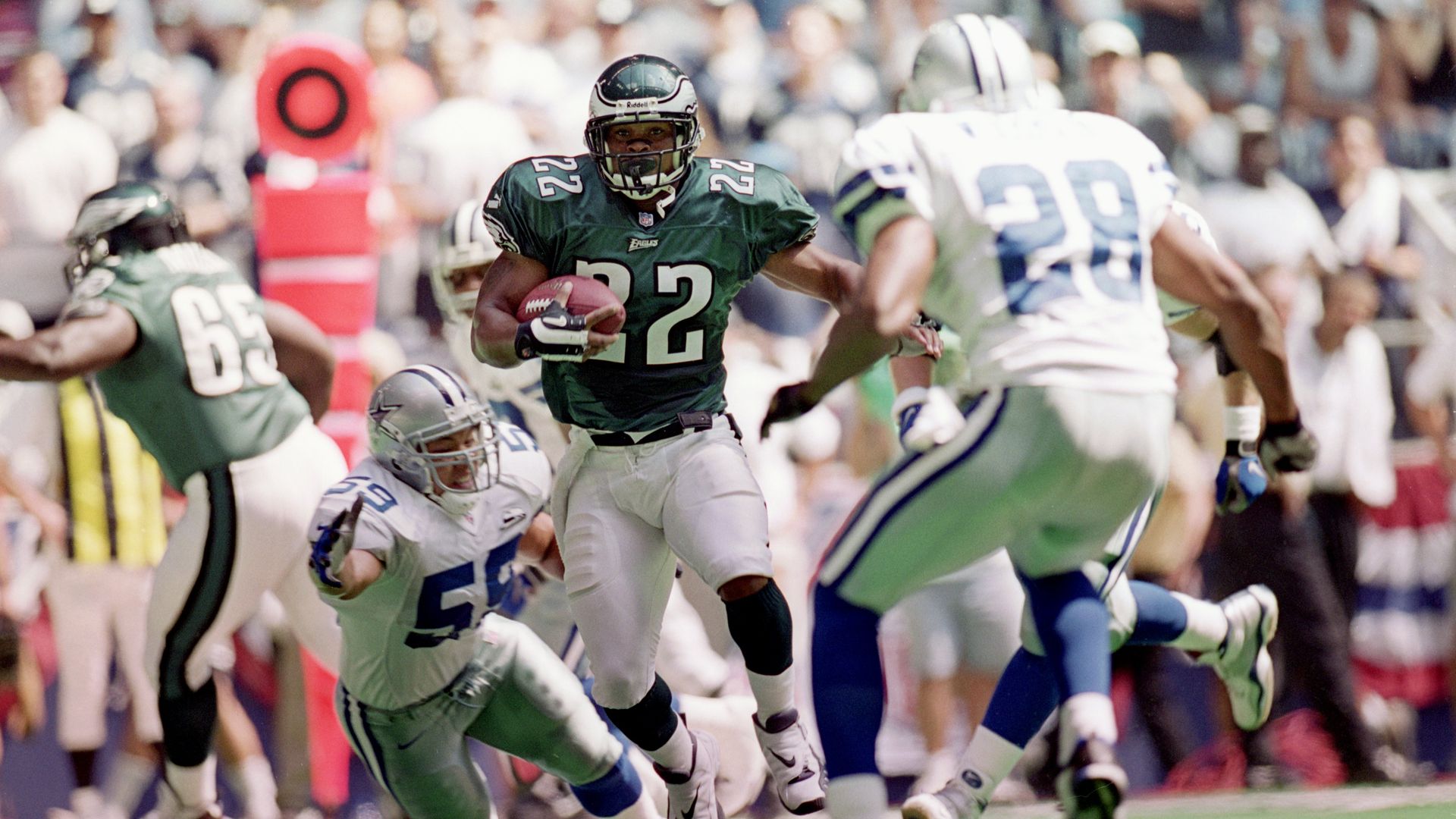 A football player in white and green runs pass another football player in white and blue