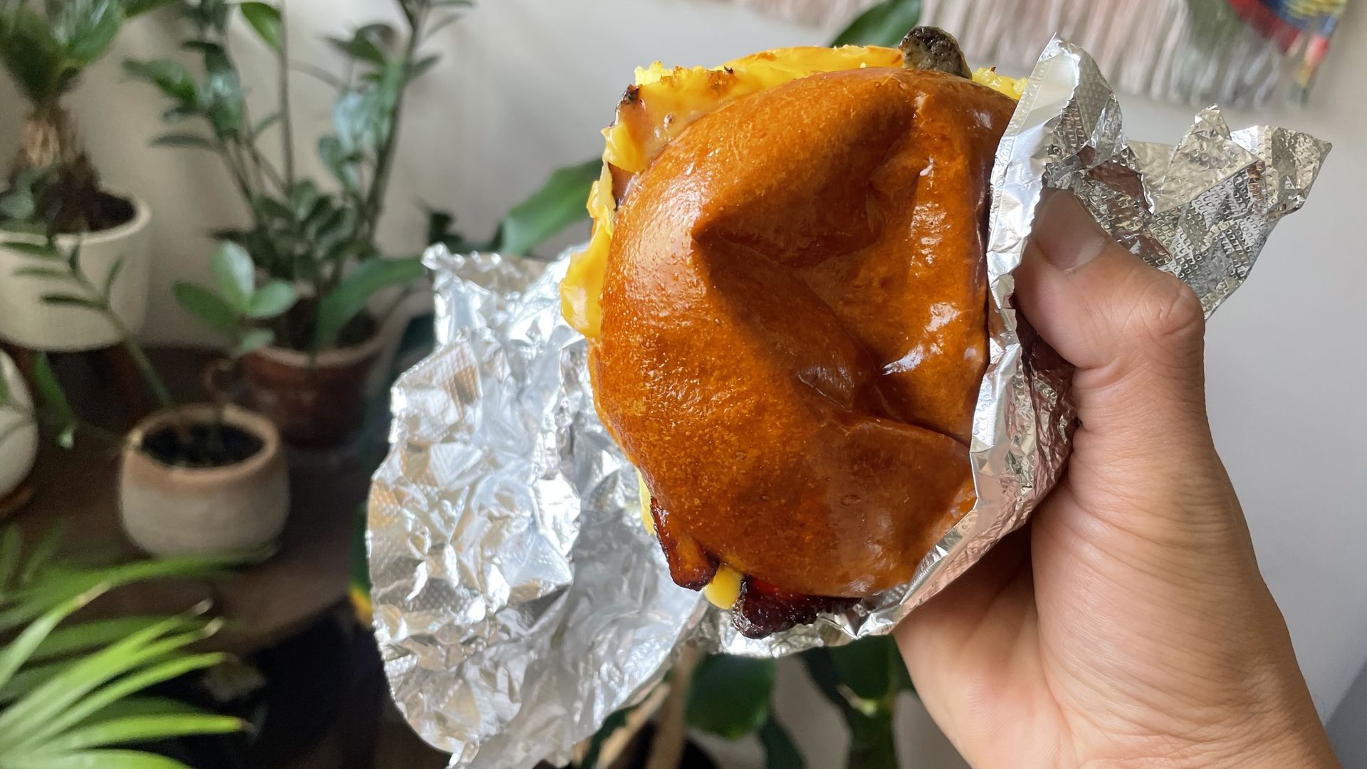 A breakfast sandwich covered partially in aluminum foil. 