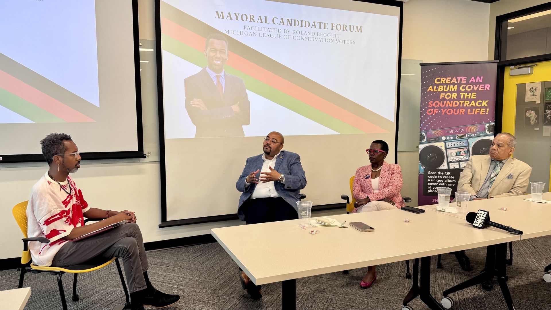 Four people seated in a panel discussion at a mayoral candidate forum