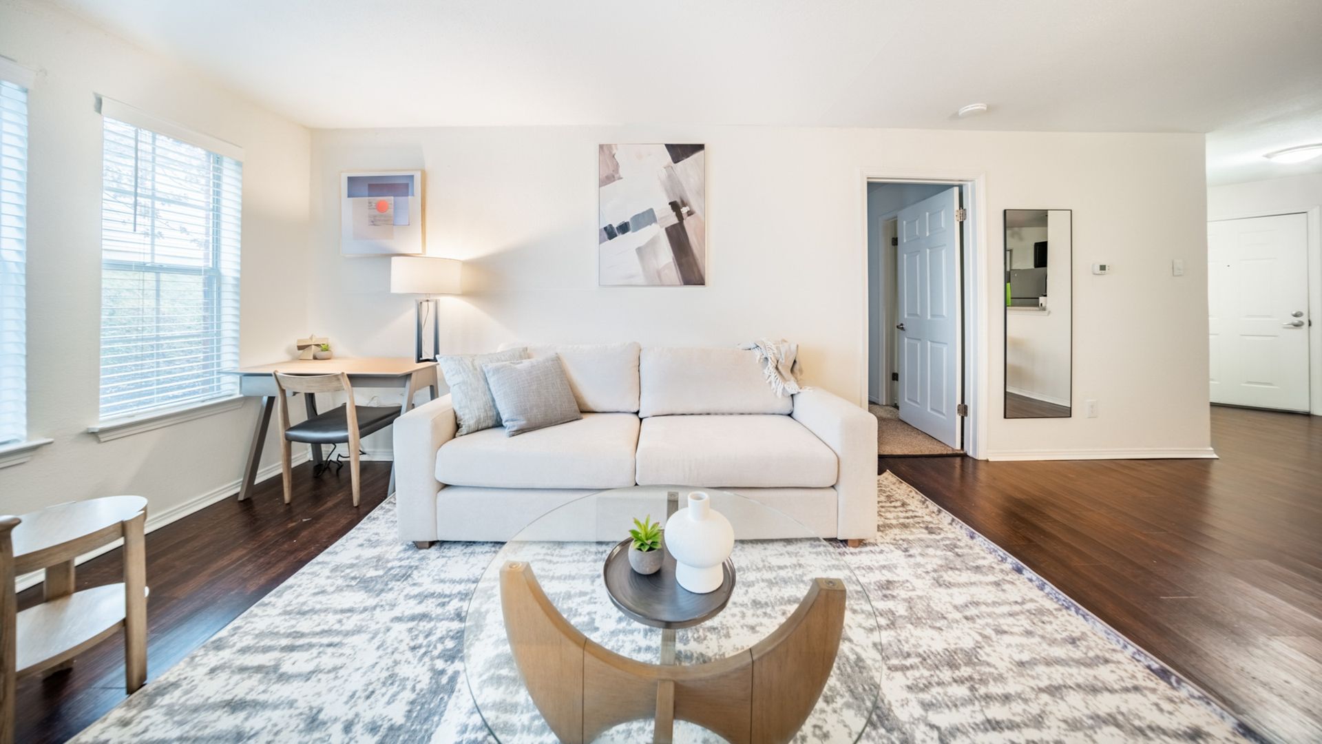 Living room of a townhouse with white couch, rug and hardwood floors.