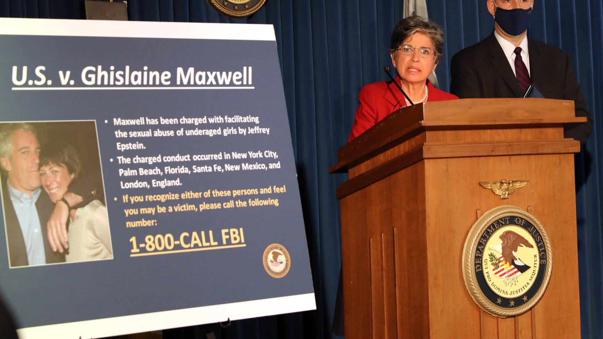 An FBI poster with a photo of Maxwell and Epstein is next to a podium where an official is speaking.