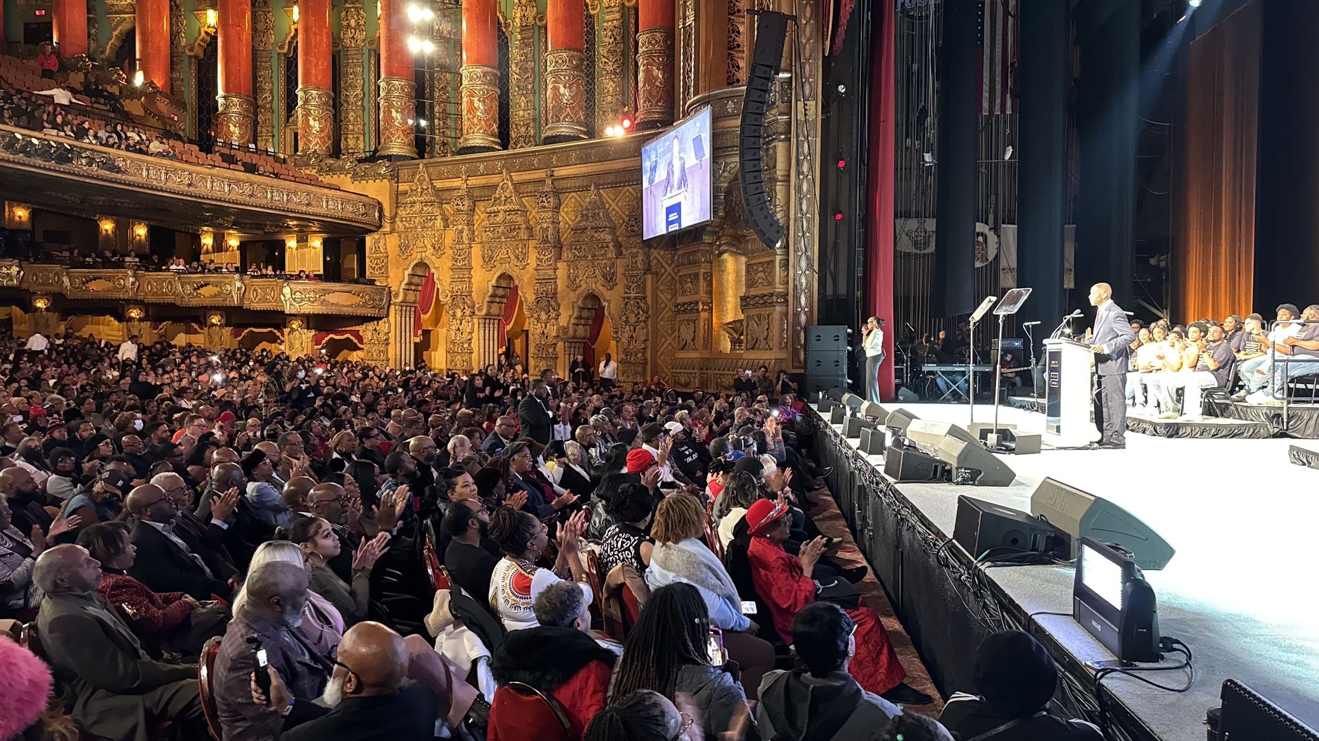 Kinloch speaks to a large crowd in the theater.