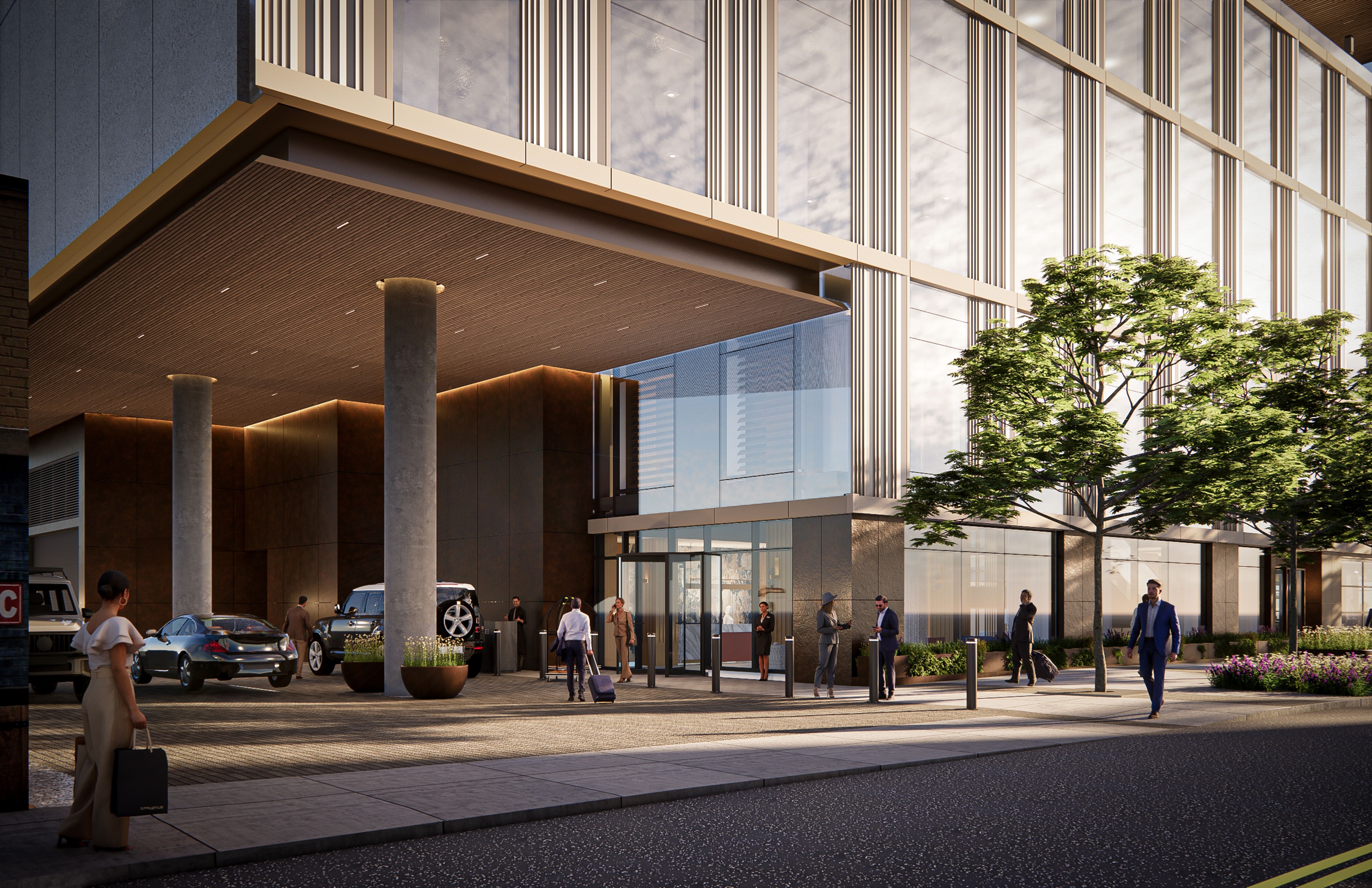 Modern glass office building with tall vertical metal fins, a covered drop-off area supported by concrete columns, and pedestrians on a sidewalk; trees flank the facade and street with cars.