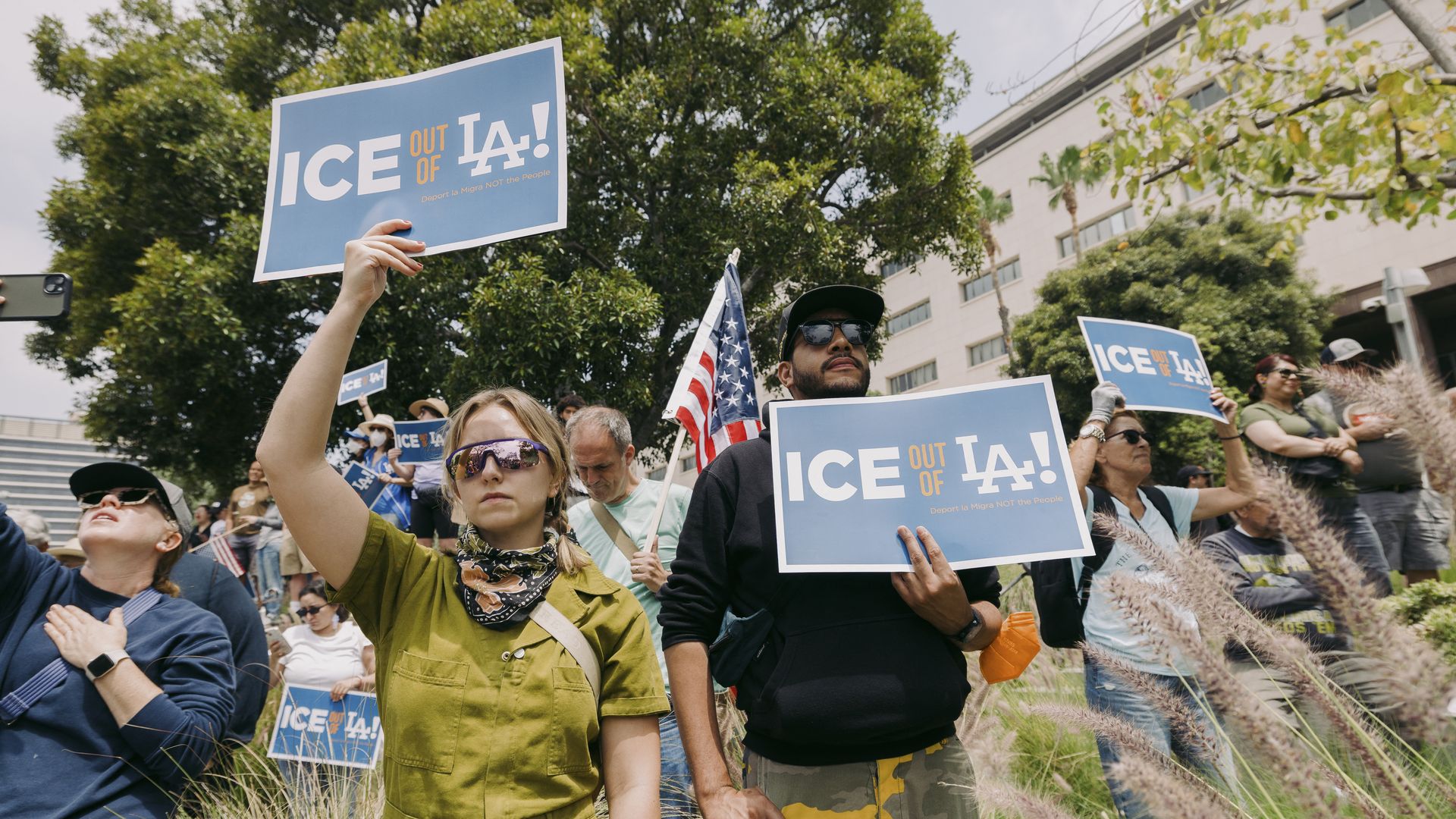 Protesters hold signs that read "ICE out of LA" 