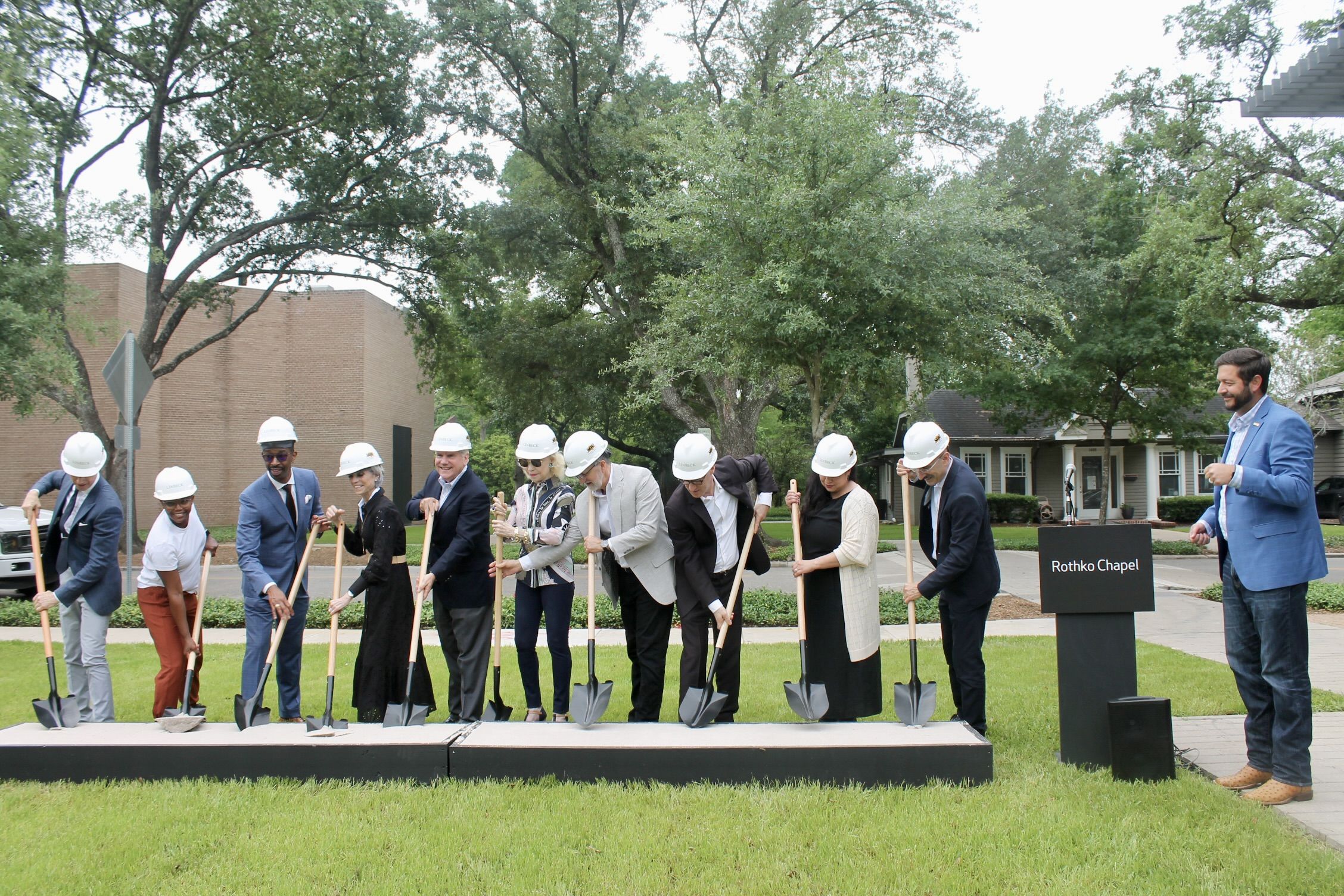Photo of people posing as they dig into the ground. 