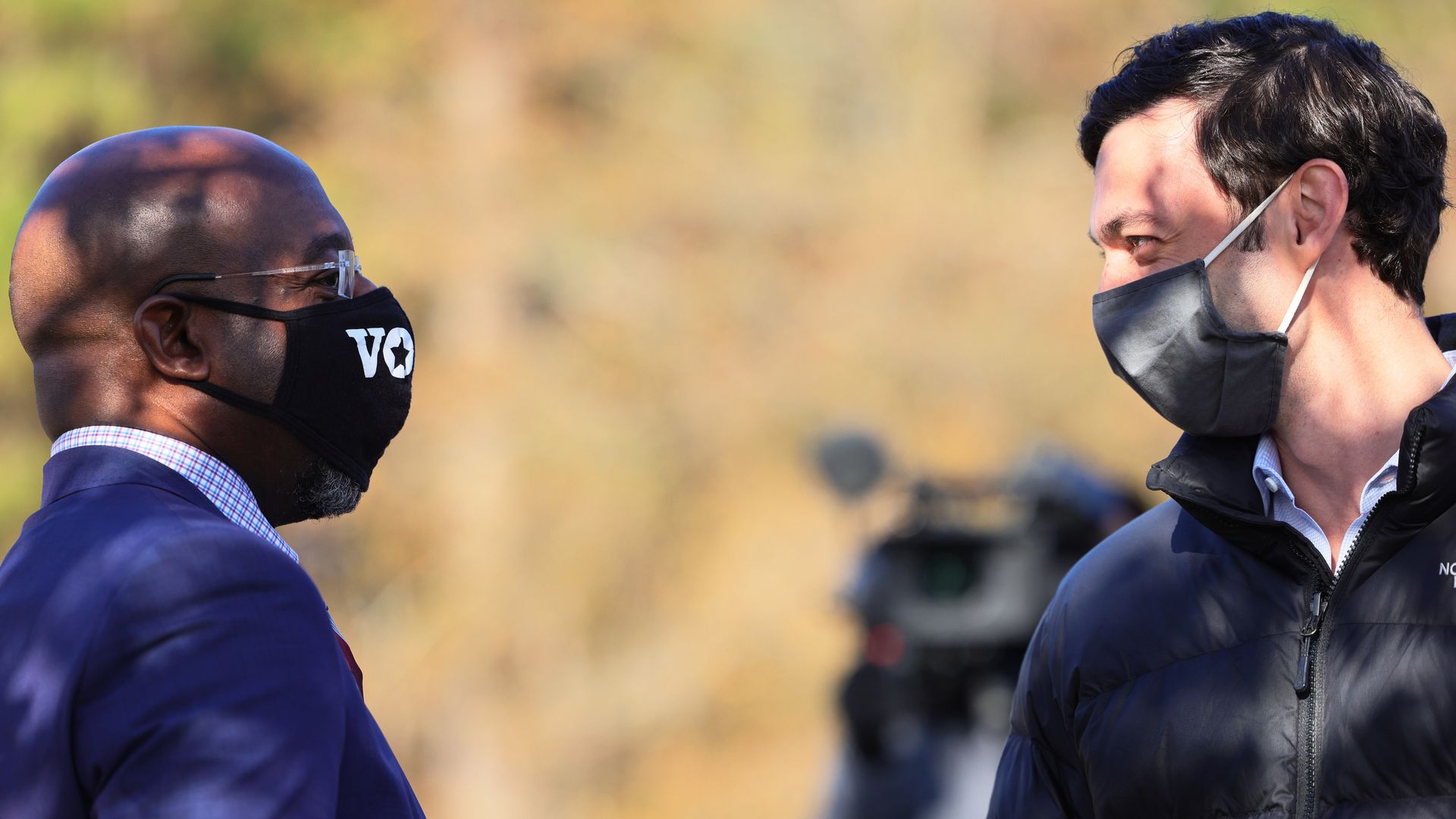 Picture of Rev. Raphael Warnock and Jon Ossoff looking at each other while wearing masks.
