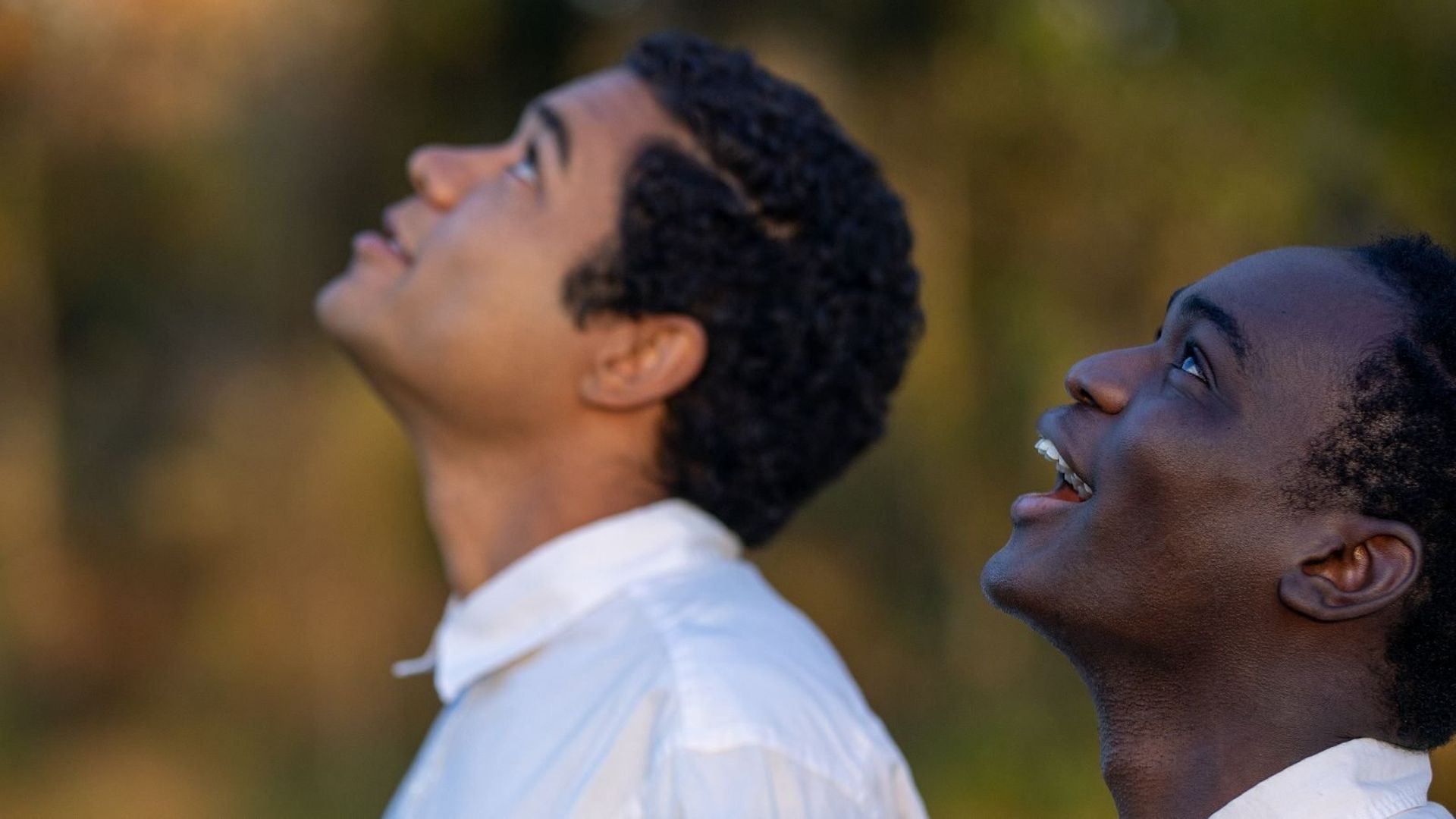 A photo of two young men as they look toward the sky with awe.