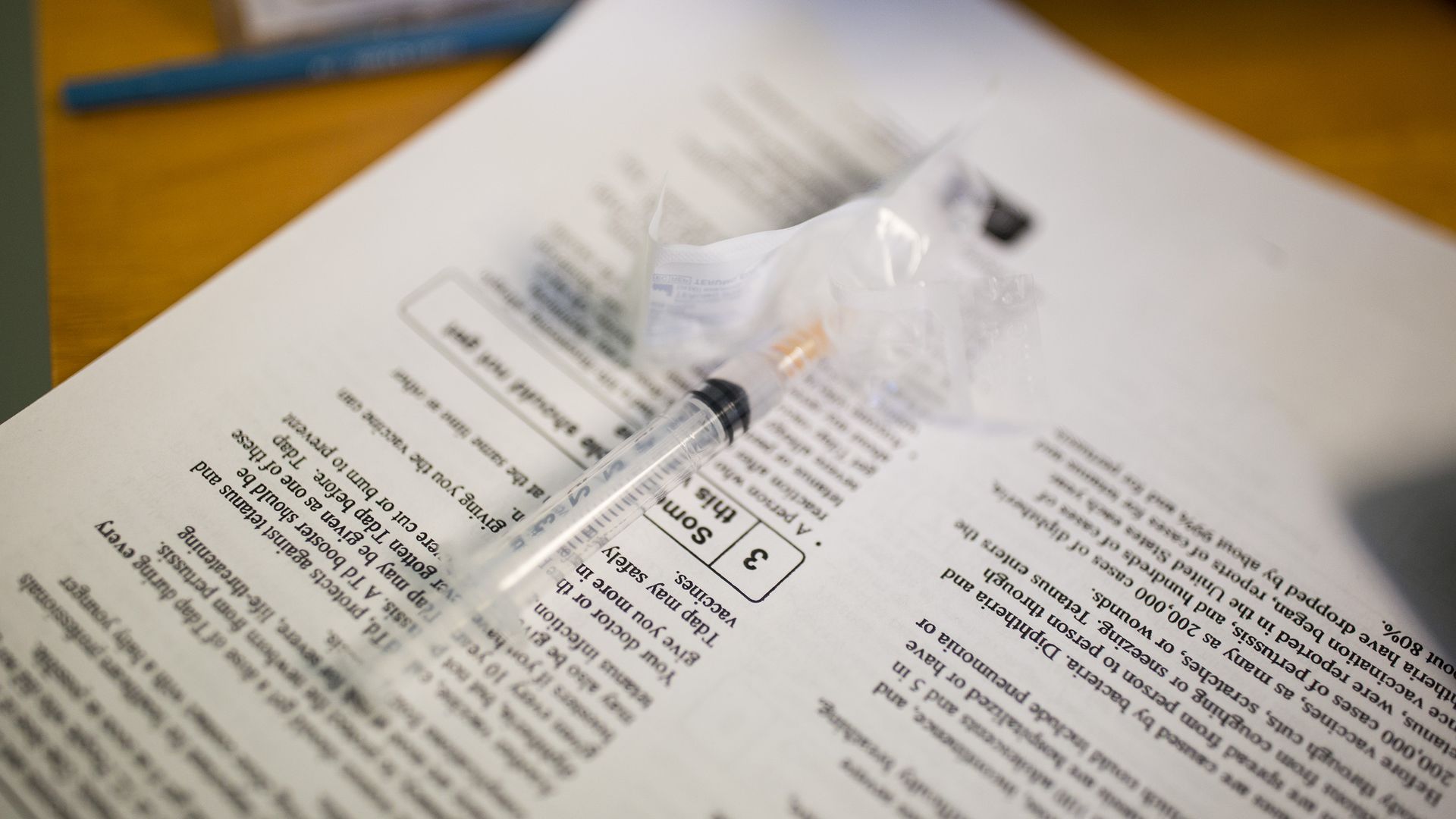In this image, a syringe sits on top of a piece of paper.