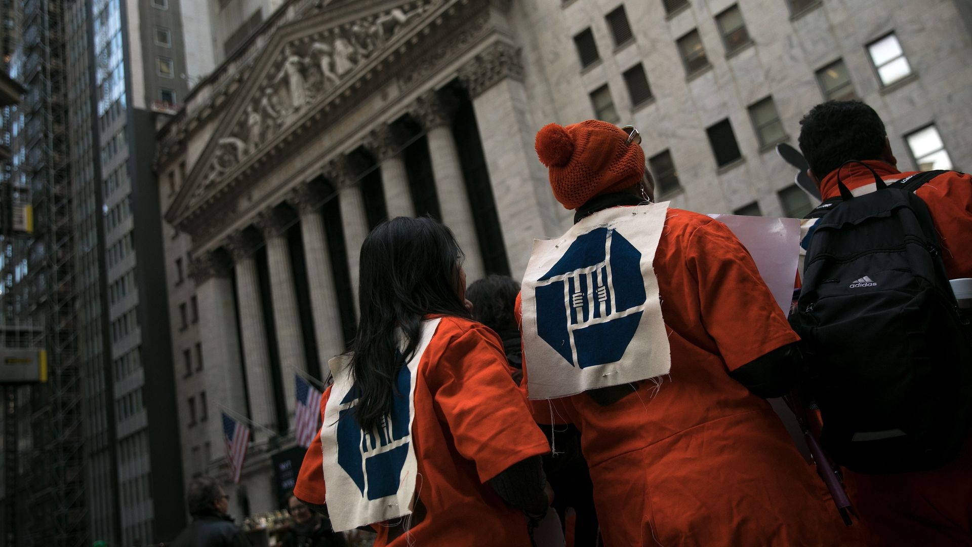 Activists in orange jump suits with prison emblems on their backs. 