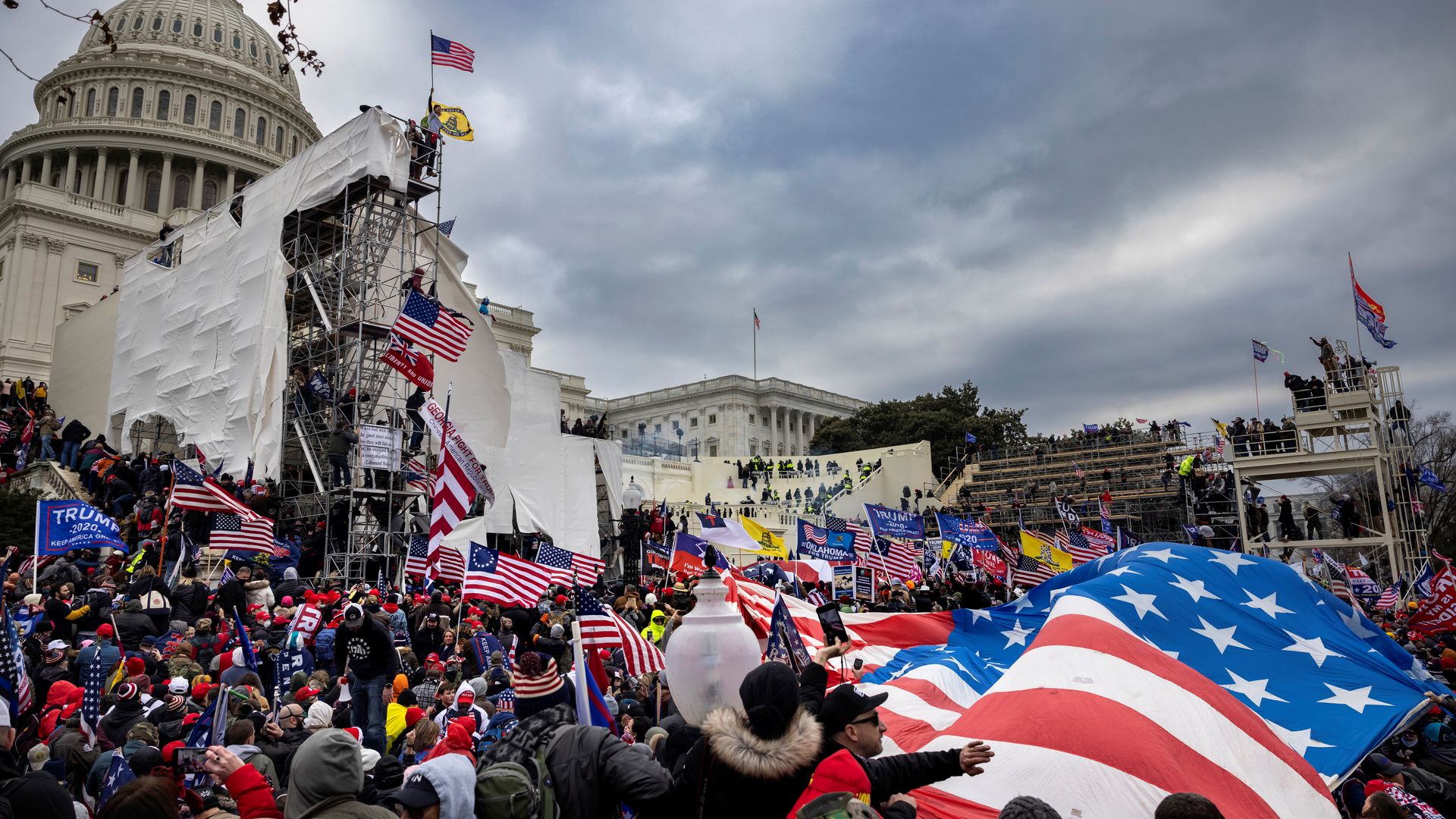 A photo of the Capitol with rioters in front of it 