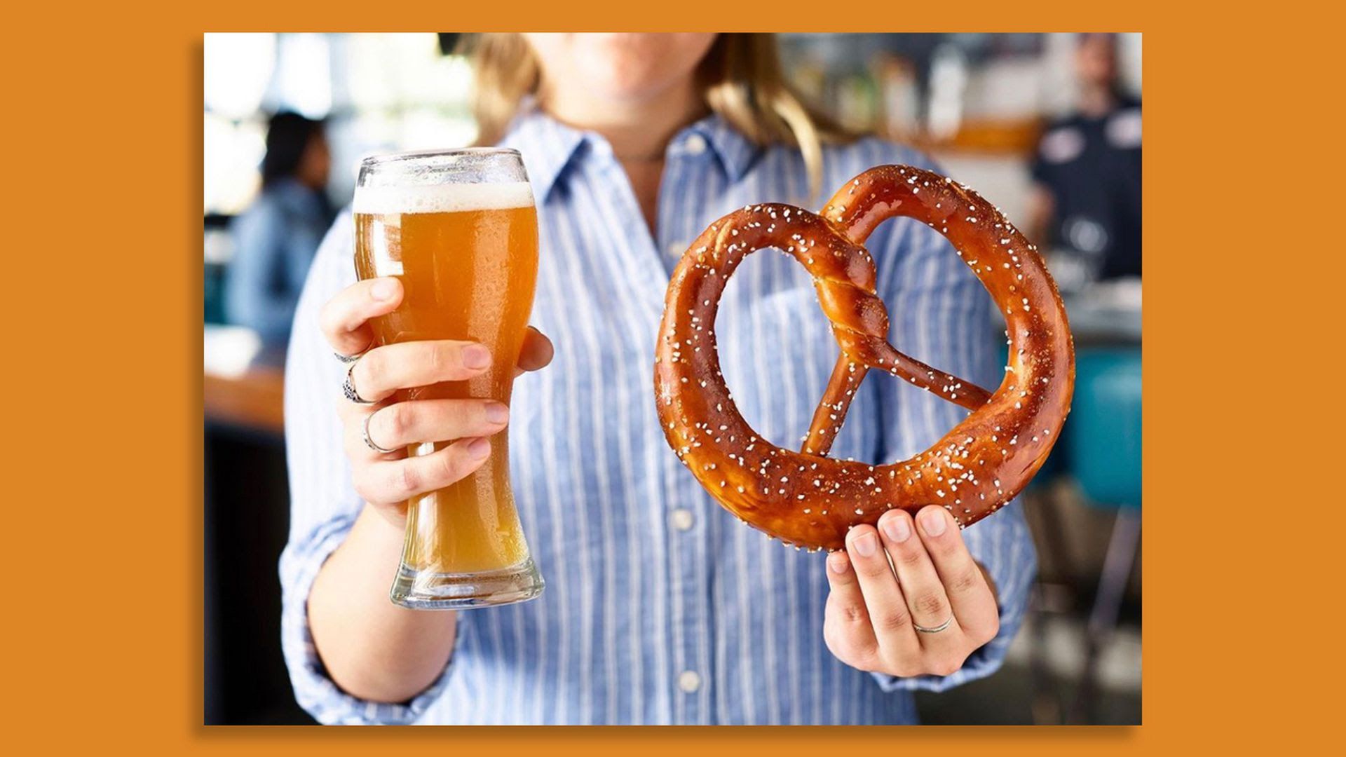 A beer and Bavarian soft pretzel from Von Elrod's are help up by a woman in a blue shirt