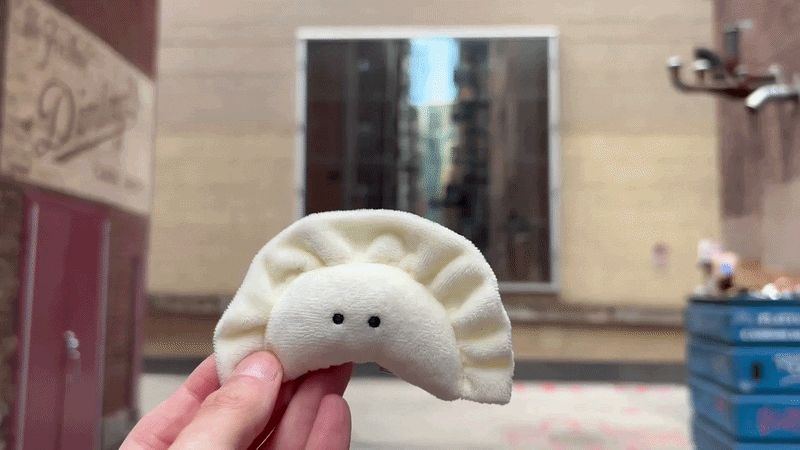 A plush pierogi toy in front a black screen with flashing red dots