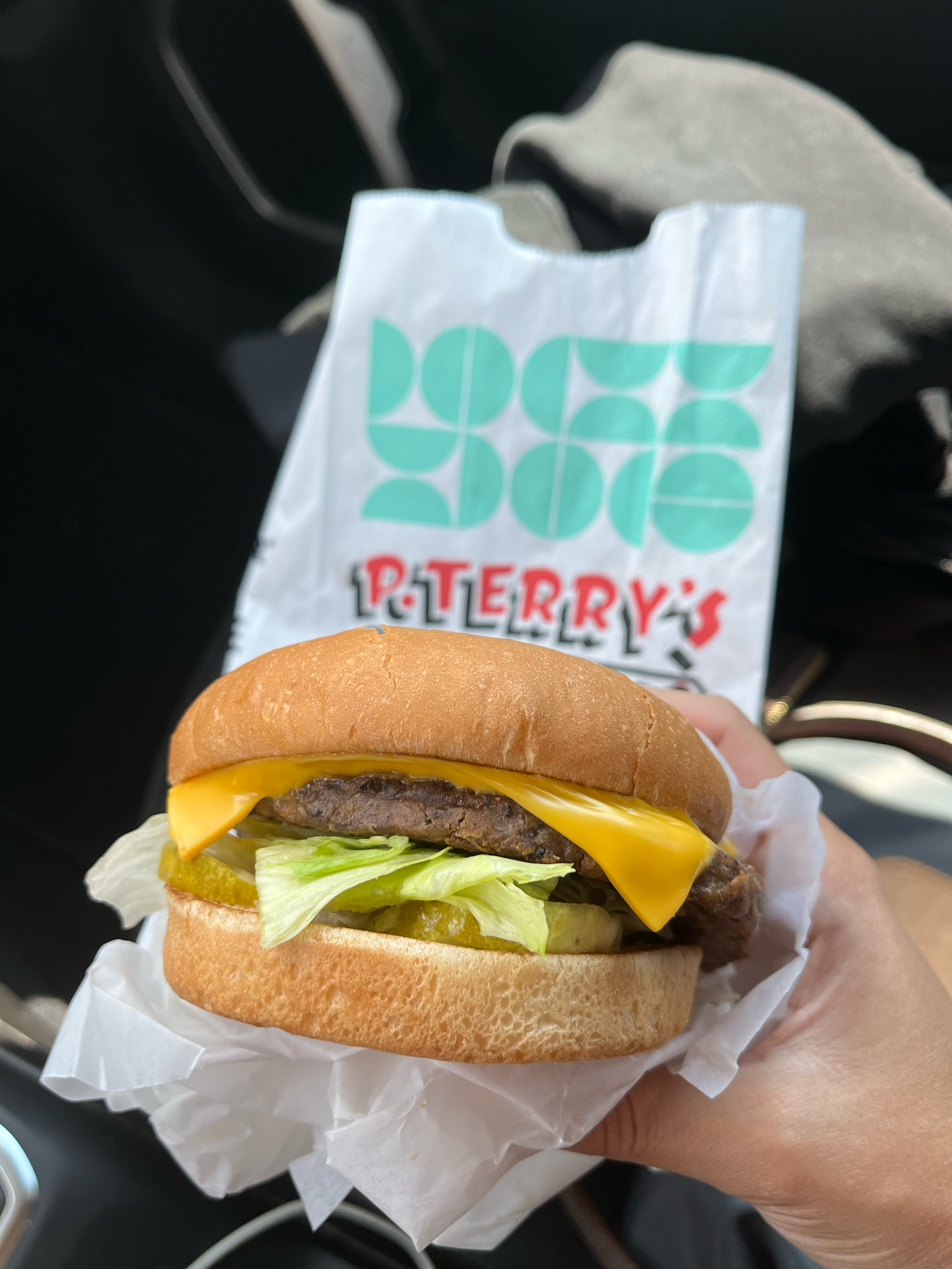 burger held in front of a P. Terry's bag in drive thru