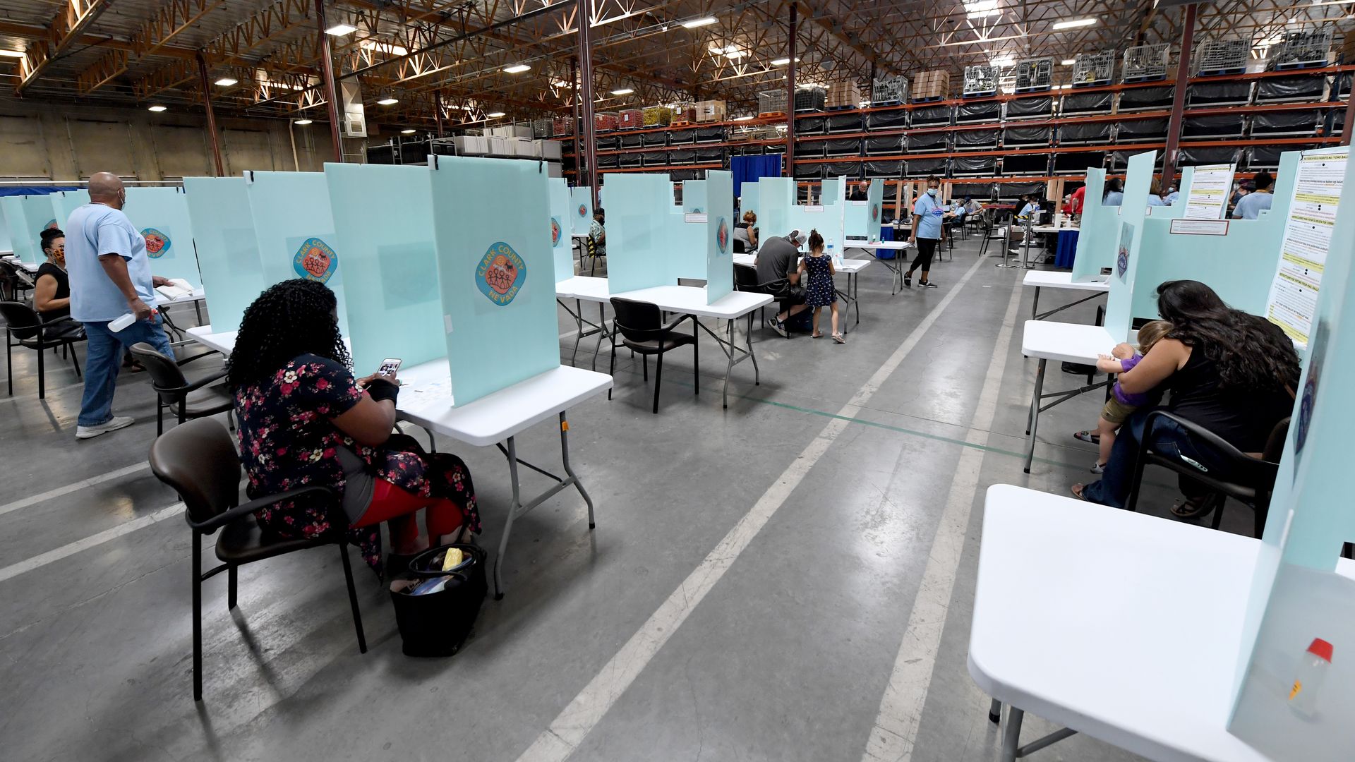 People fill out ballots using voter privacy partitions.