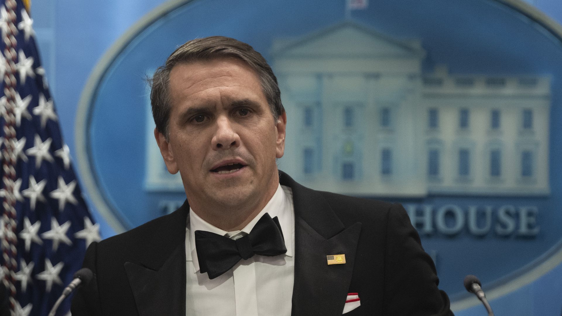 Acting Attorney General Todd Blanche, in a tuxedo, standing in front of the White House logo and an American flag. 