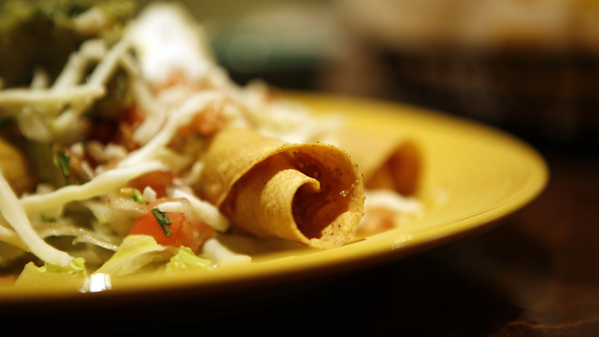 A taquito on a plate with Mexican sides