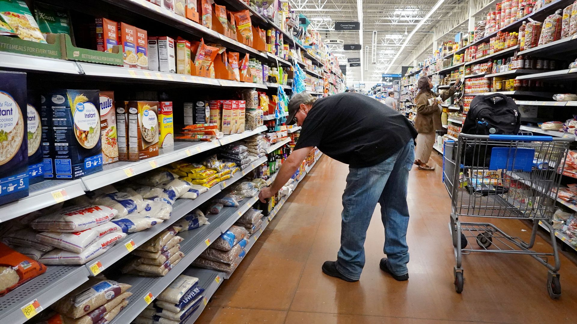 A person bending down at a grocery store shelf.