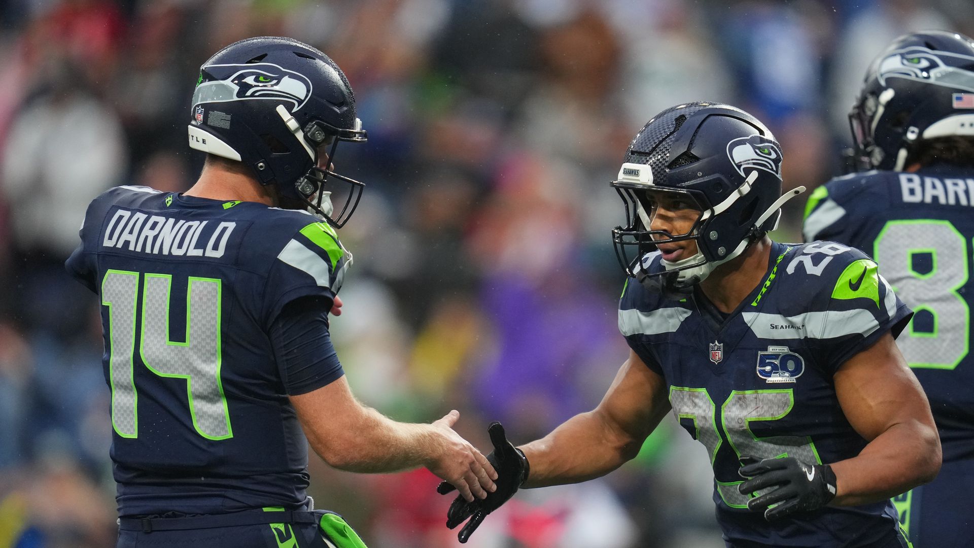 Two Seattle Seahawks shake hands on the field after a touchdown. 