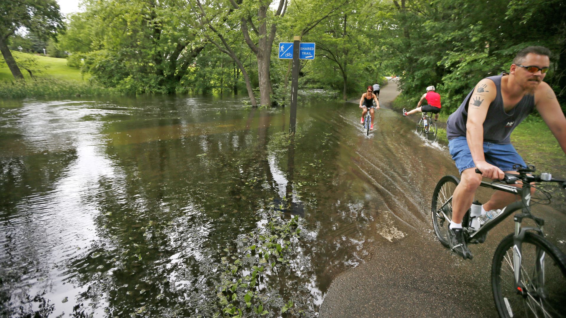 people biking along a path that flooded in the spring
