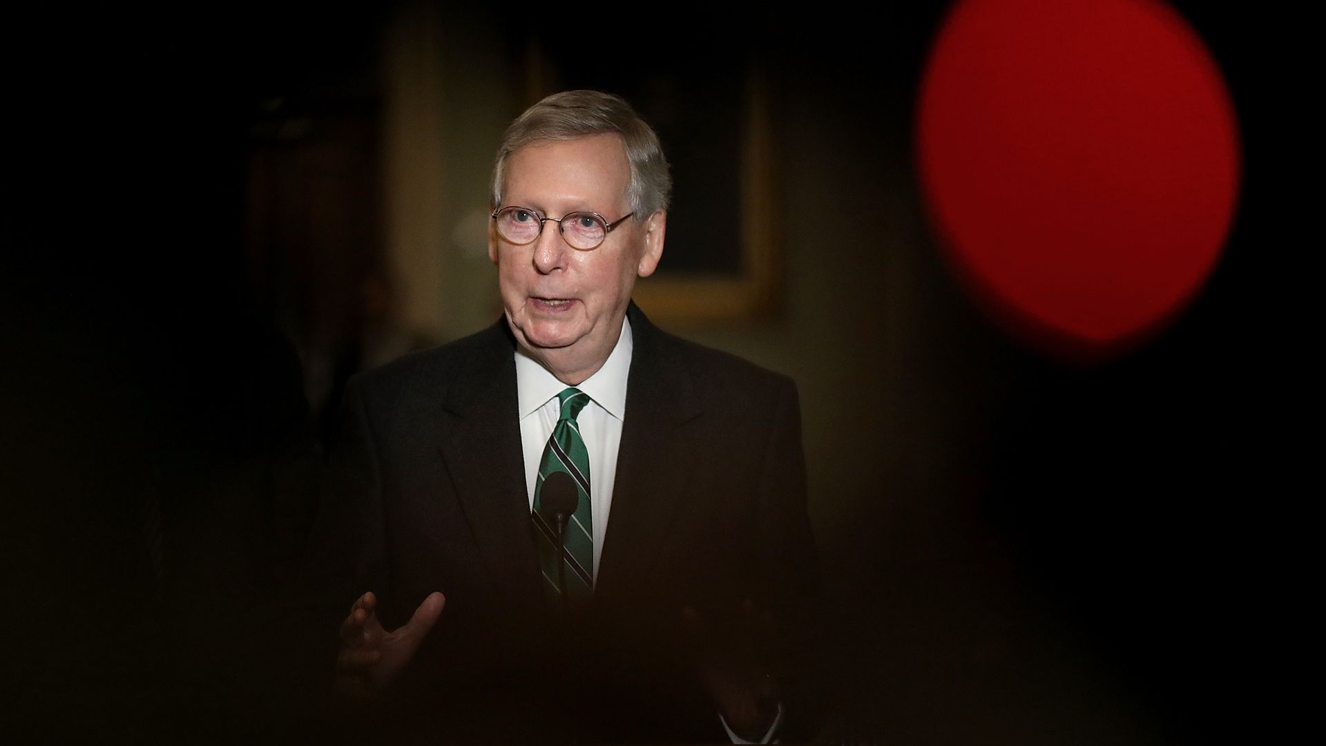 Mitch McConnell stand in a spotlight surrounded by darkness