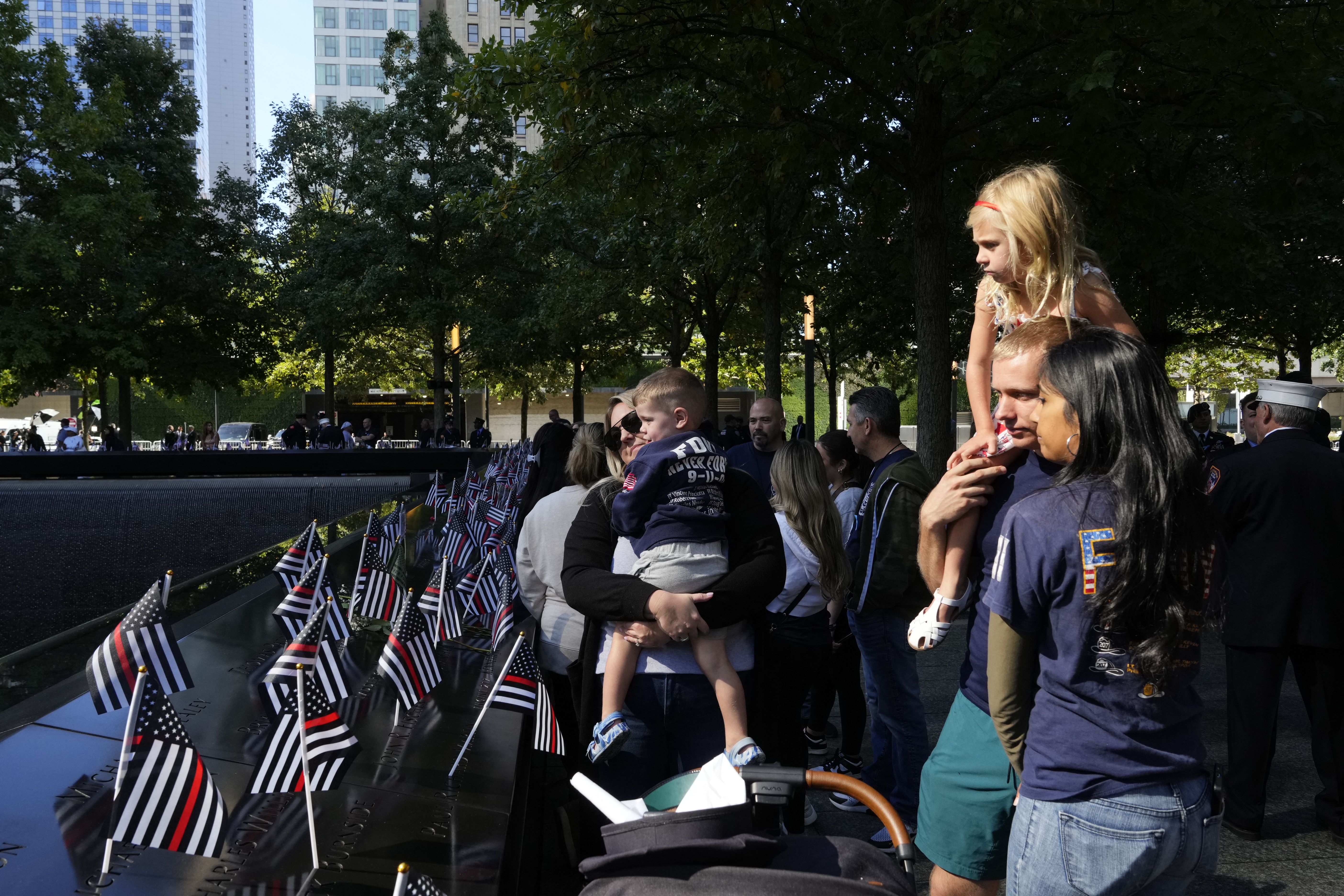 Firefighters with their family look at the 9/11 memorial on the 23rd anniversary of the September 11 terror attack on the World Trade Center at Ground Zero, in New York City on September 11,