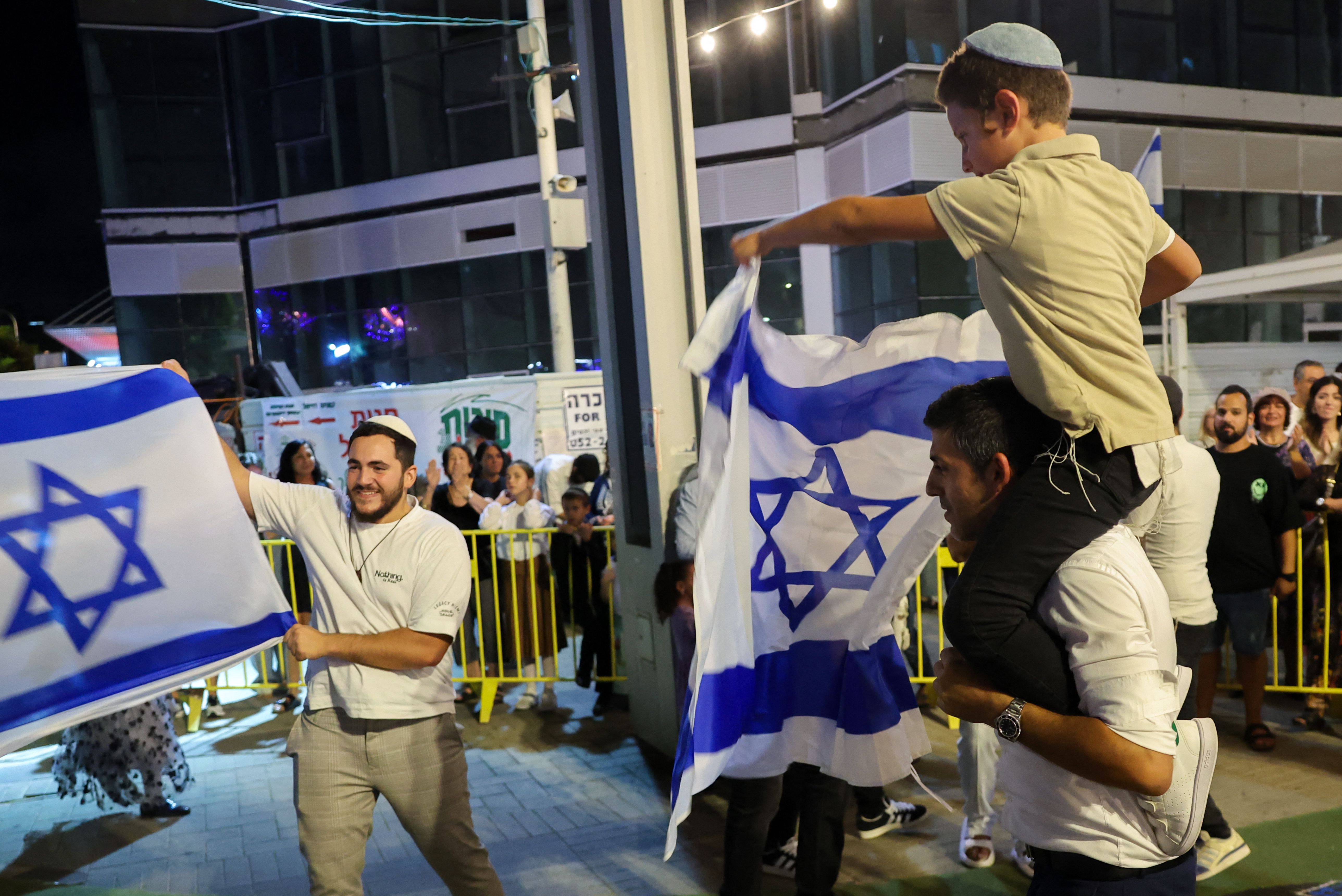 TOPSHOT - People dance and wave Israeli national flags as they celebrate the news of the death of Hamas leader Yahya Sinwar, in the Israeli costal city of Netanya, on October 17, 2024. Israel said on October 17 its forces killed Sinwar, accused of masterminding the October 7, 2023 attack, calling it