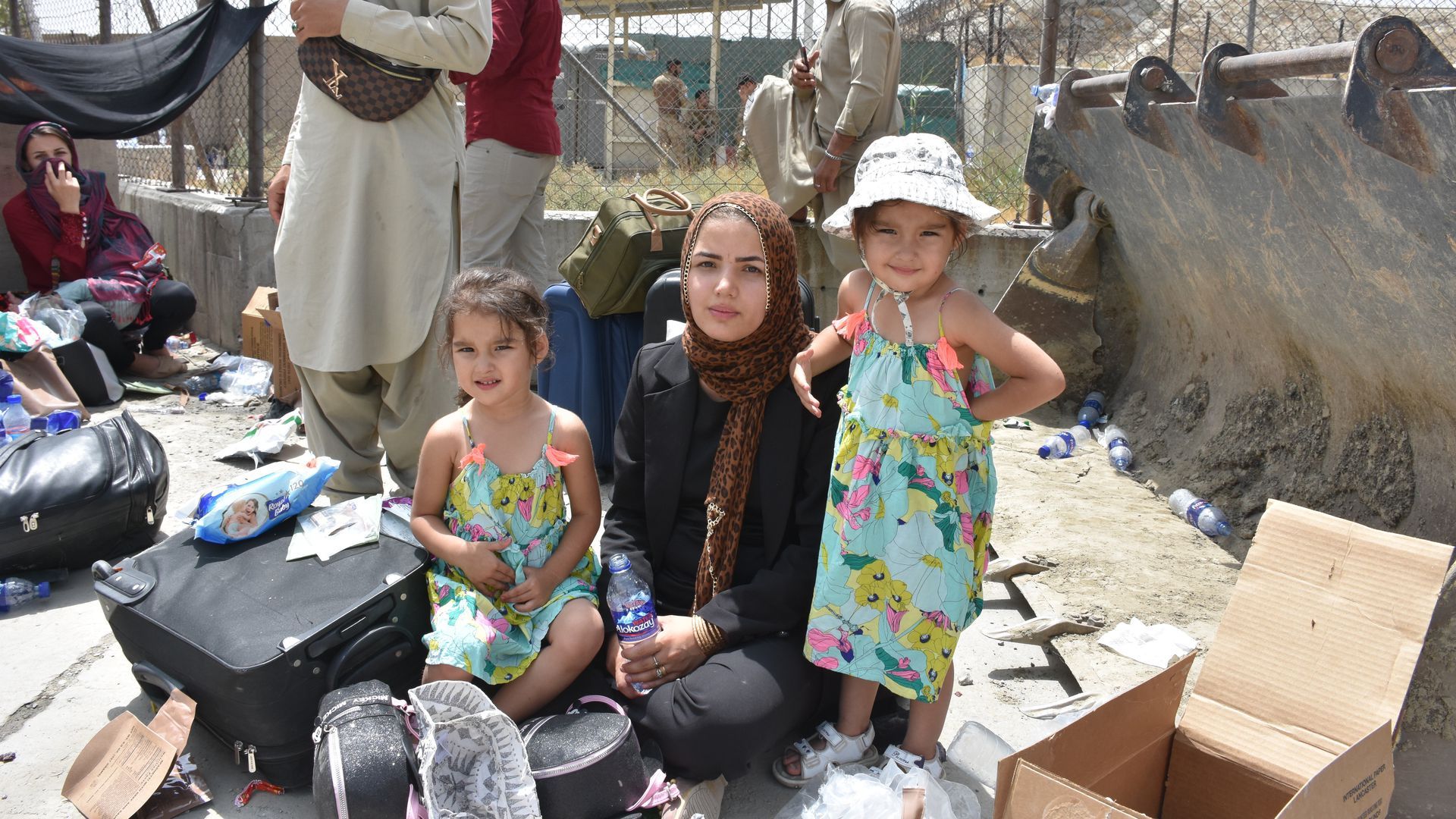 A photo of Afghan refugees -- a mother and her two daughters -- sitting alongside their belongings 