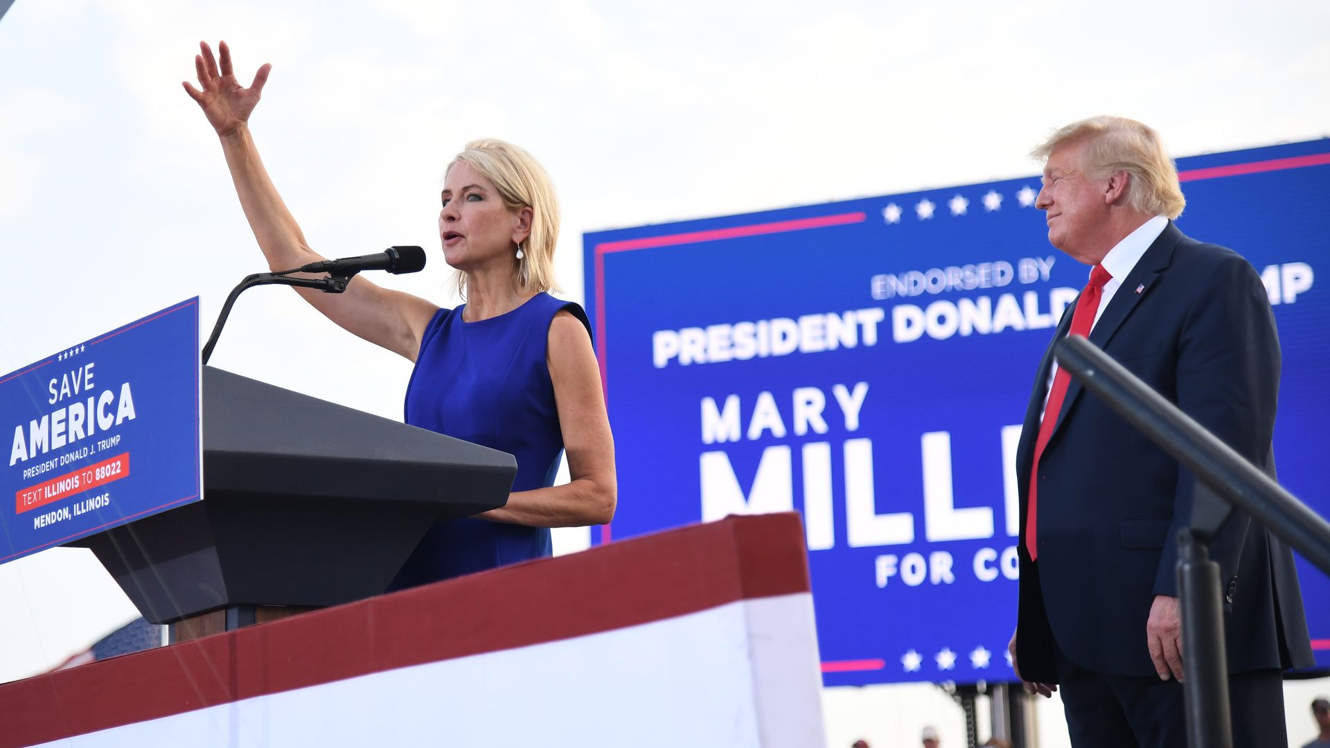 Photo of a woman standing behind a podium at a campaign rally. 