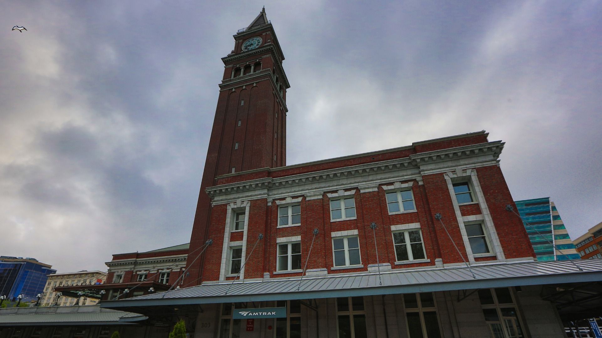 A brick building with a clock tower is seen against a cloudy sky in Seattle. 