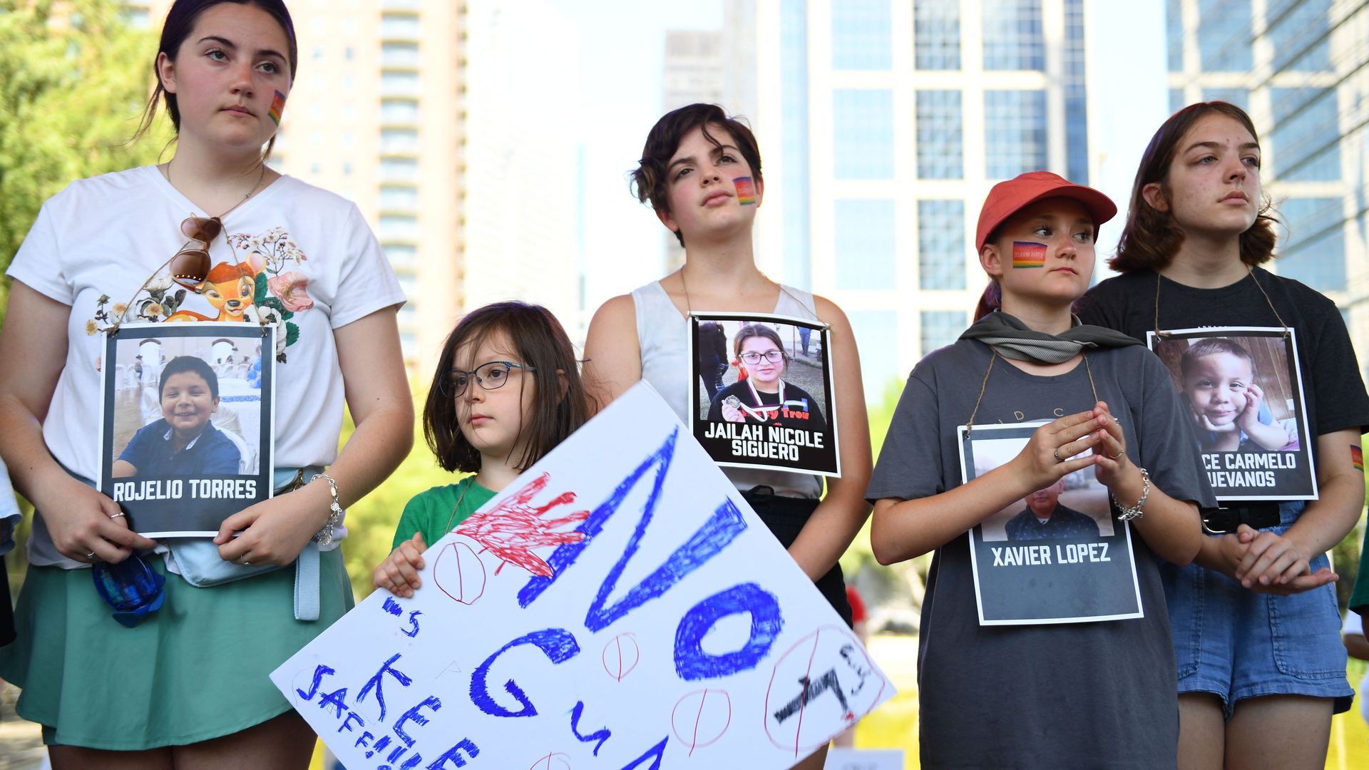 Photo of kids and teens holding pictures of the victims of the Uvalde shooting. One child holds a sign that says "No guns, keep me safe!!!"