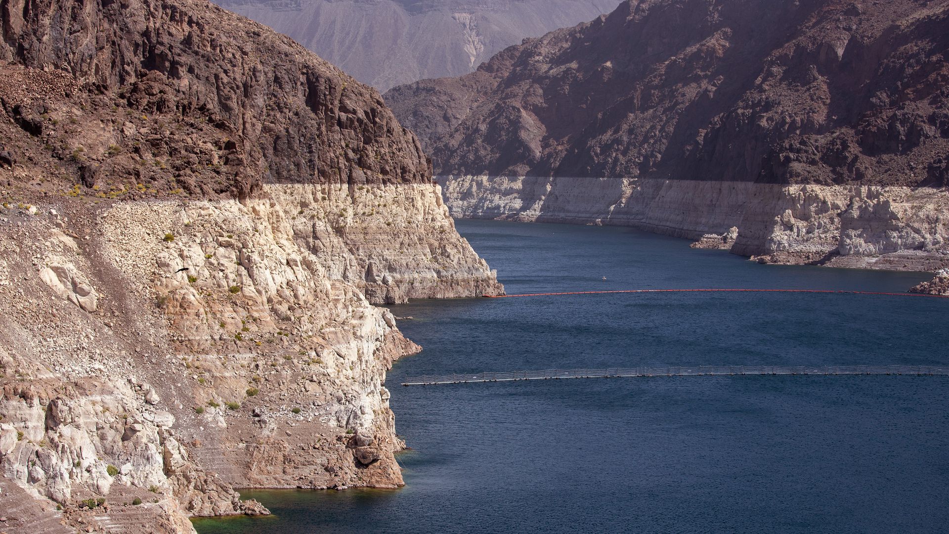 A river running through a canyon with discolorations on the sides that show how far water levels have dropped.