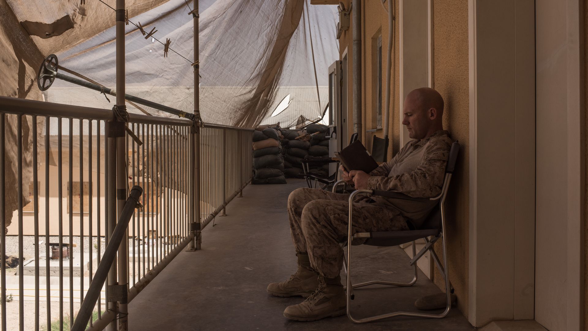 A U.S. marine reads a book sitting in a chair. 