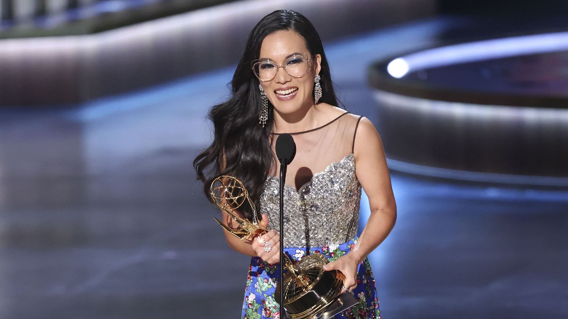 Photo shows Ali Wong smiling on stage and holding an Emmy.