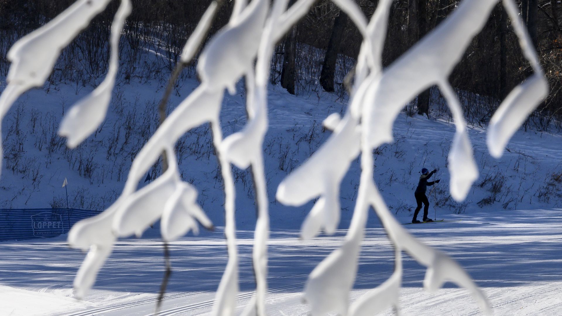 In this image, a skater turns on an outdoor ice rink in the snow 