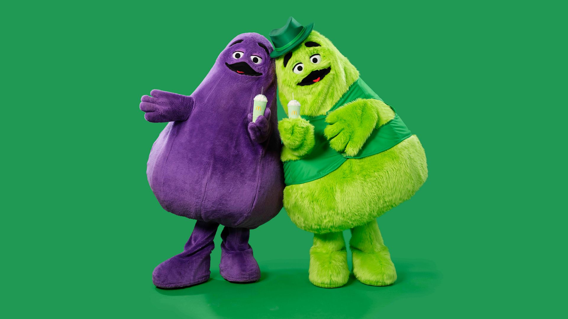A purple character and a fuzzy green character with green shakes in their hands