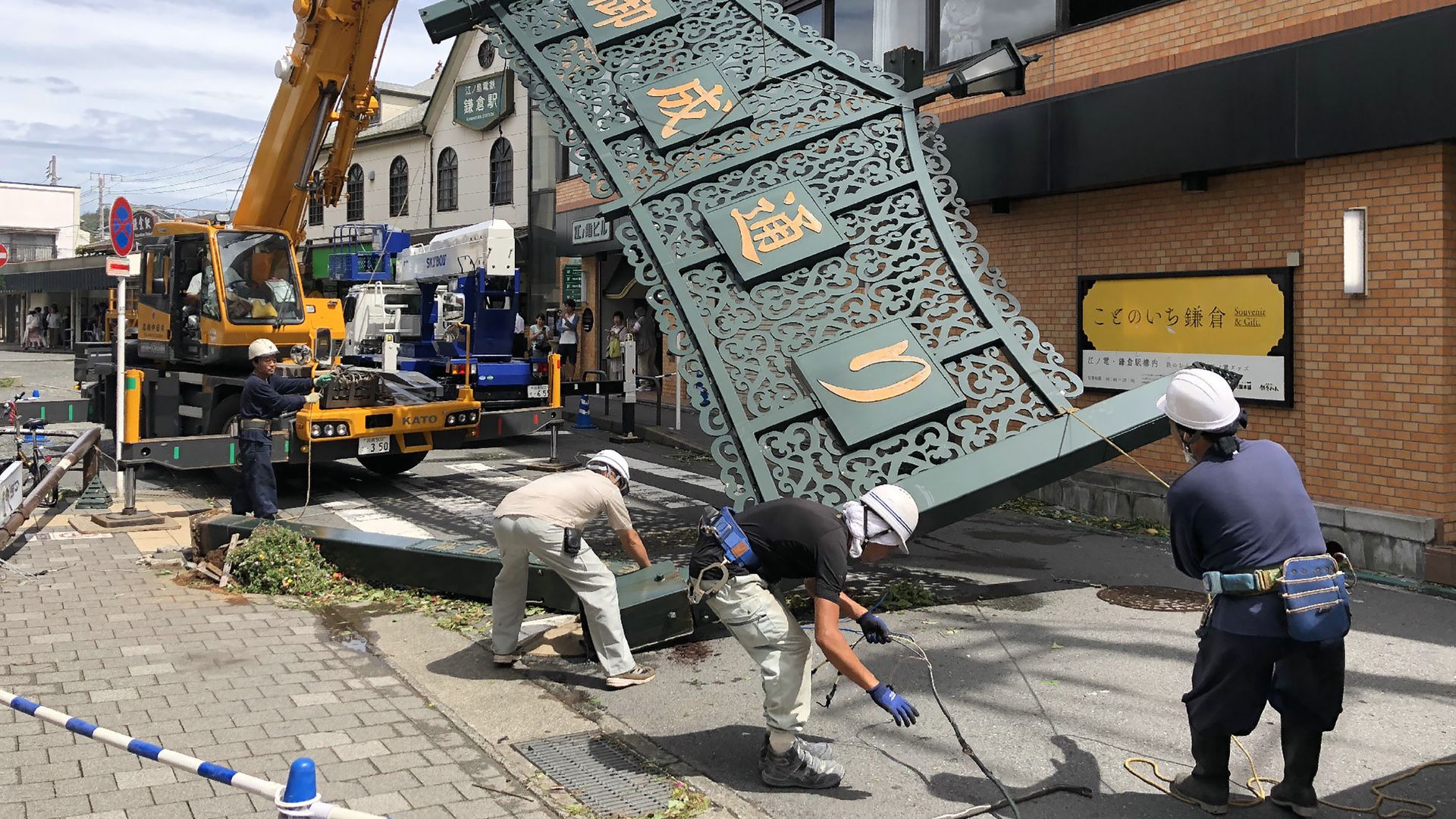 Workers remove a fallen signboard hit by typhoon Faxai in Kamakura, Kanagawa prefecture