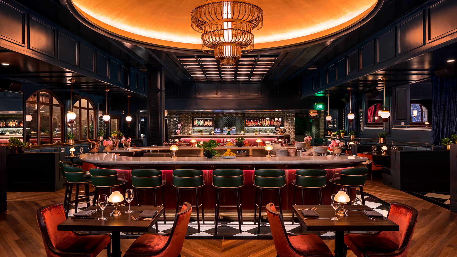 interior of a restaurant with dim lighting and red chairs and a chandelier