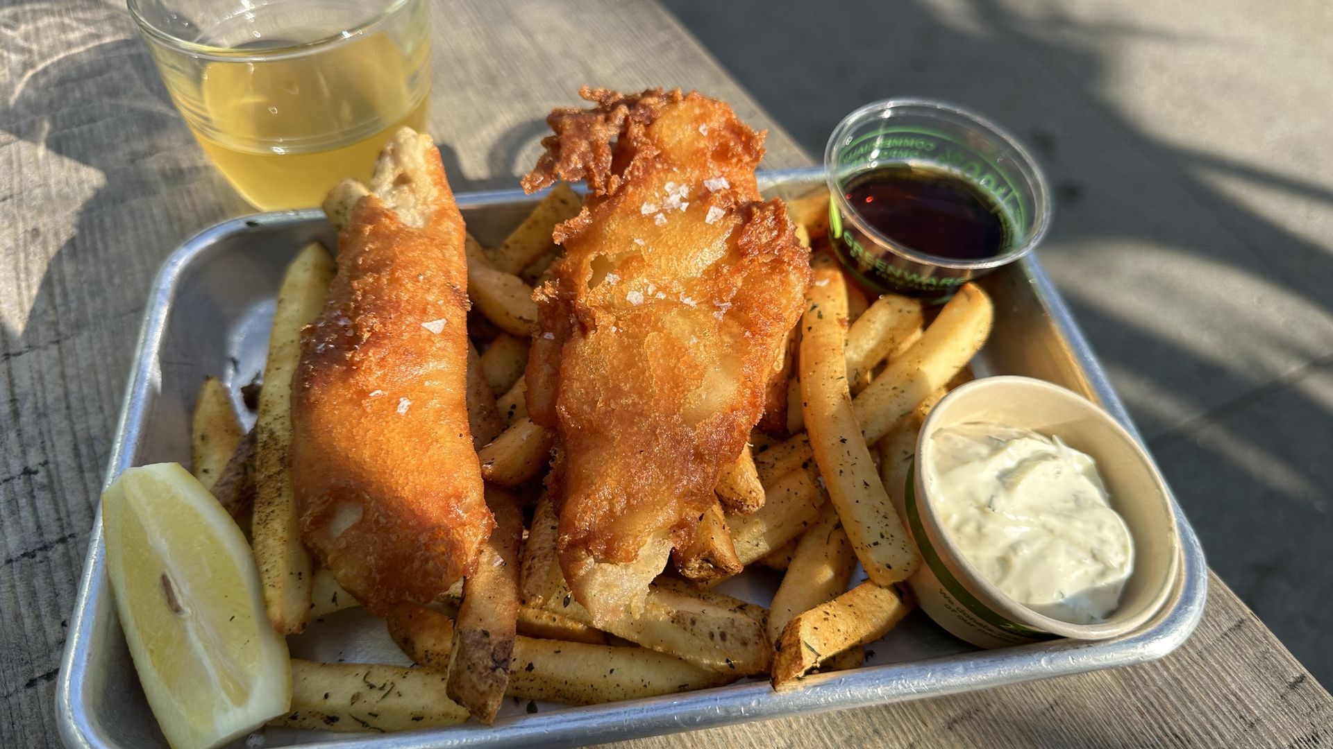 A photo of a silver platter of golden fish and chips.