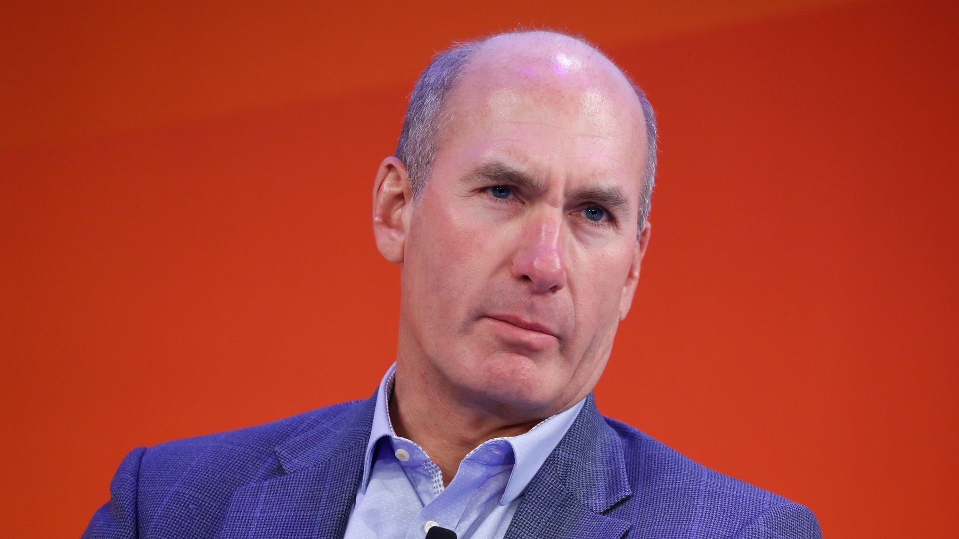 This is a photo of John Stankey against a red background