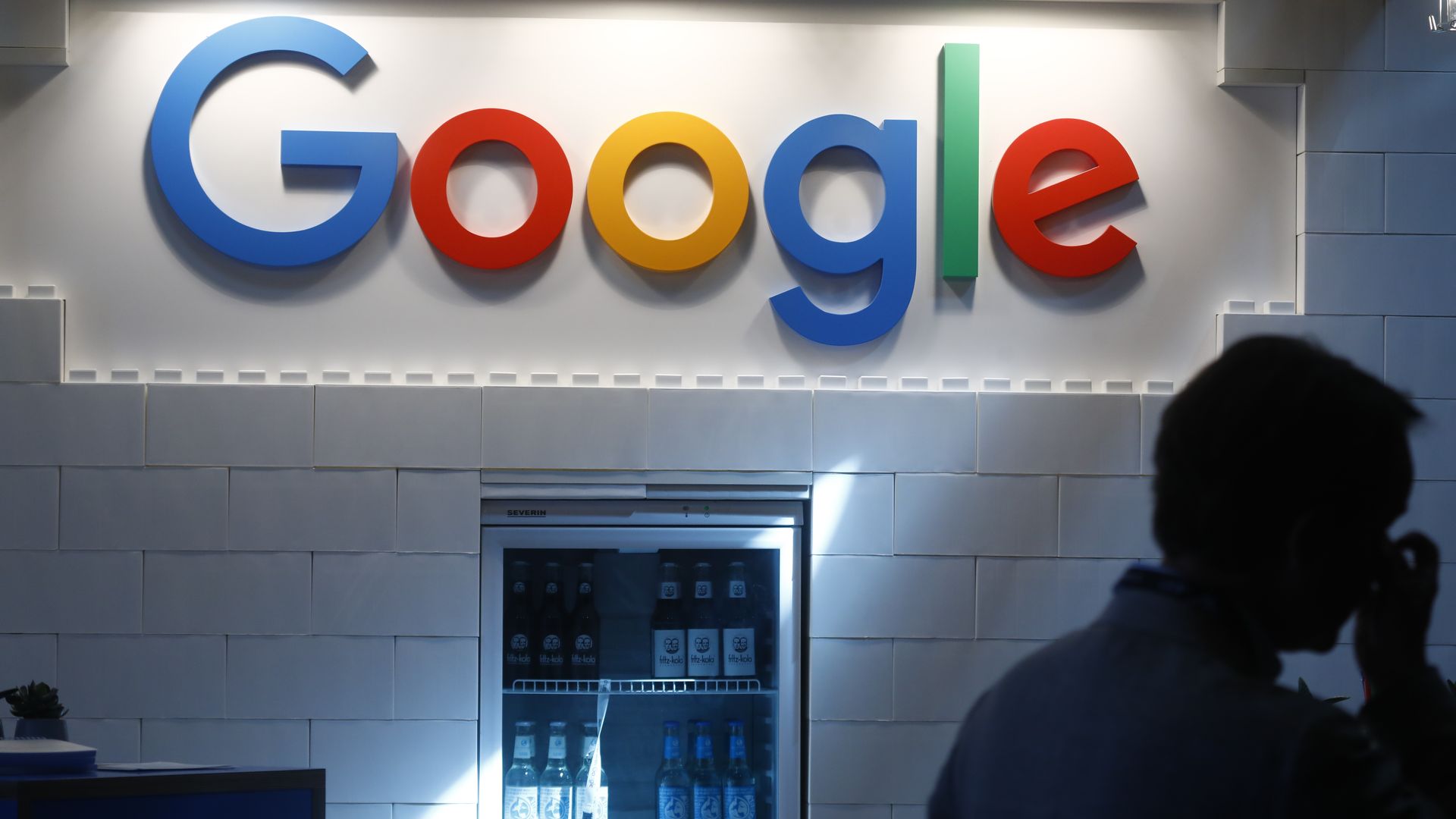 Google sign against a cinderblock wall over a refrigerator