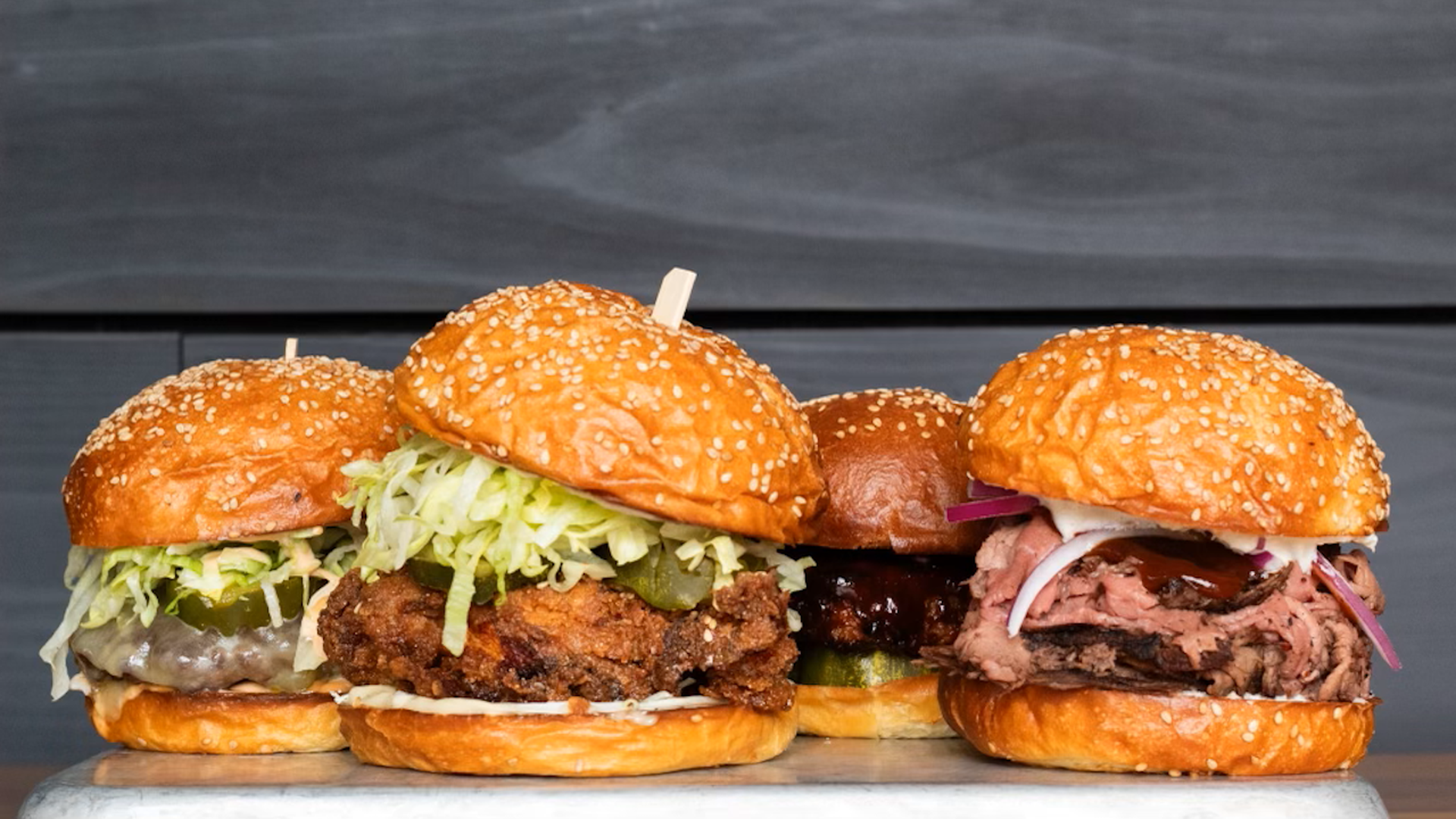 Four sandwiches on sesame seed buns including fried chicken and Baltimore pit beef