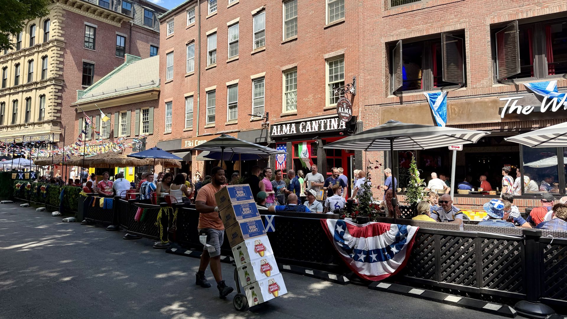 A man pushes a hand truck with six cases of beer down Union Street to one of the bars there serving throngs of Scotland fans in kilts and jerseys.