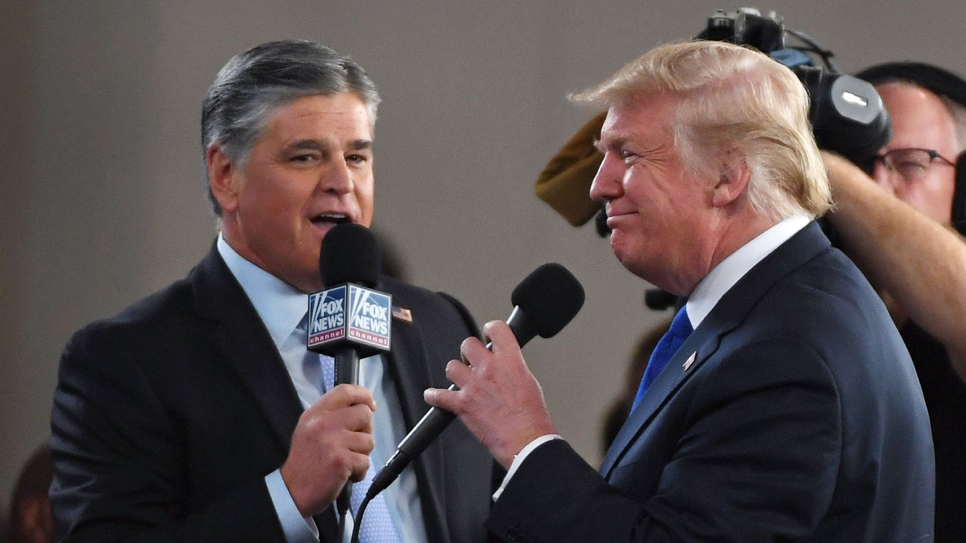 Photo of Sean Hannity and Donald Trump speaking into microphones in conversation