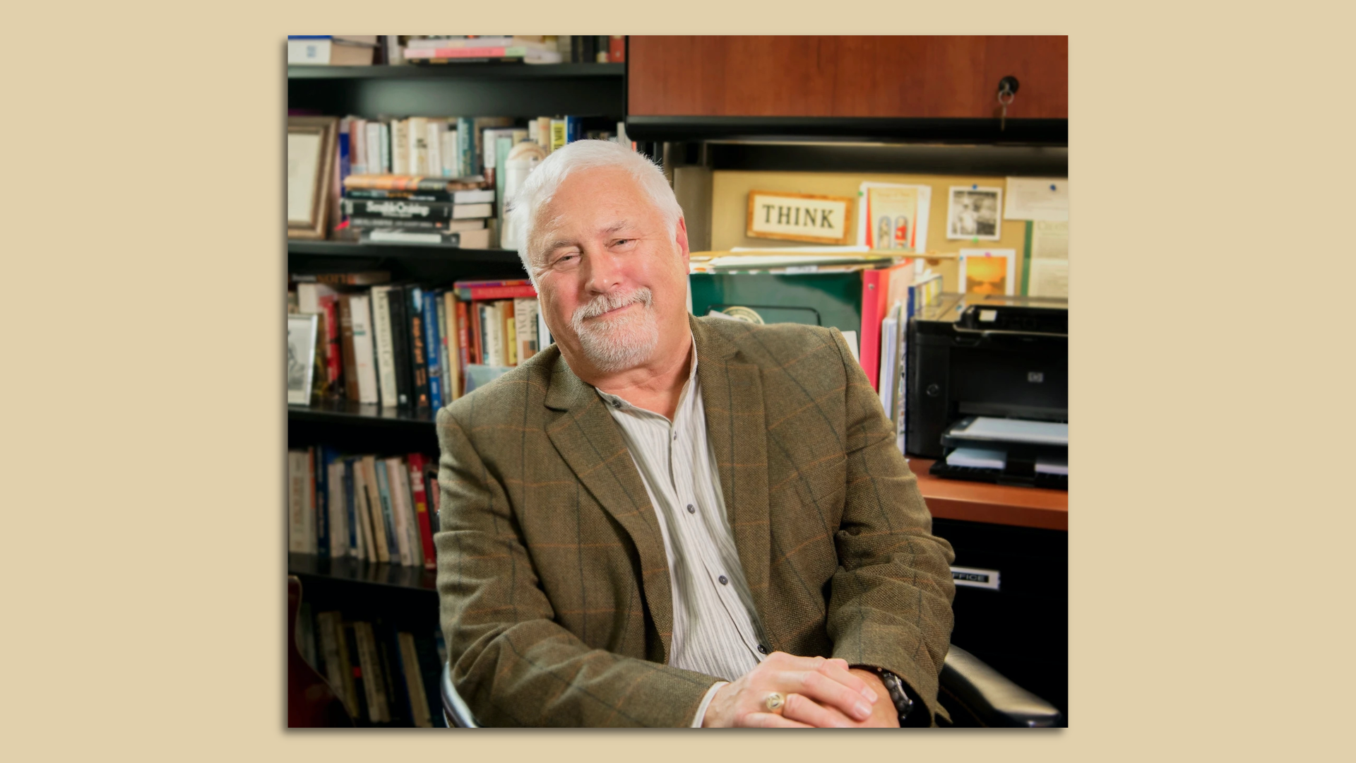 Portrait of Phillip Gerard posing in front of a desk and bookshelf